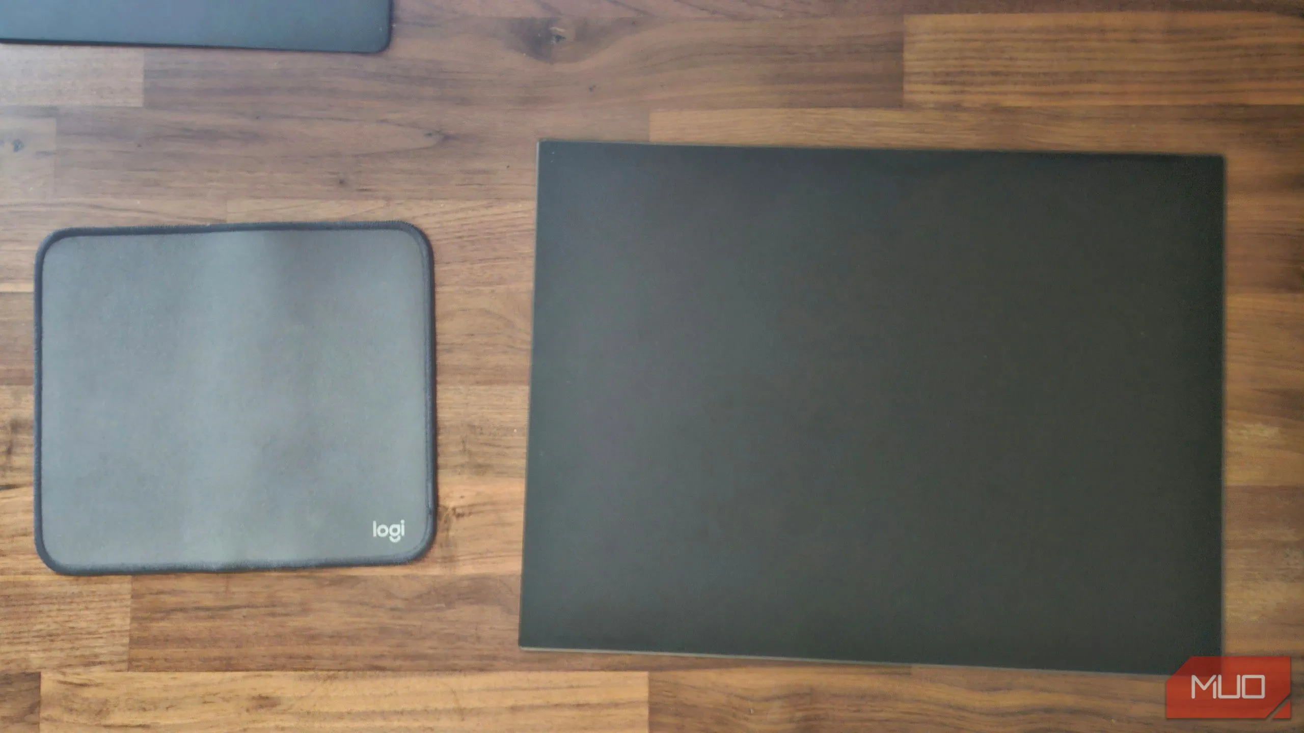 Bàn di chuột vải Logitech bên cạnh bàn di chuột kính cường lực, thể hiện sự khác biệt về thẩm mỹ và chất liệu cao cấp.