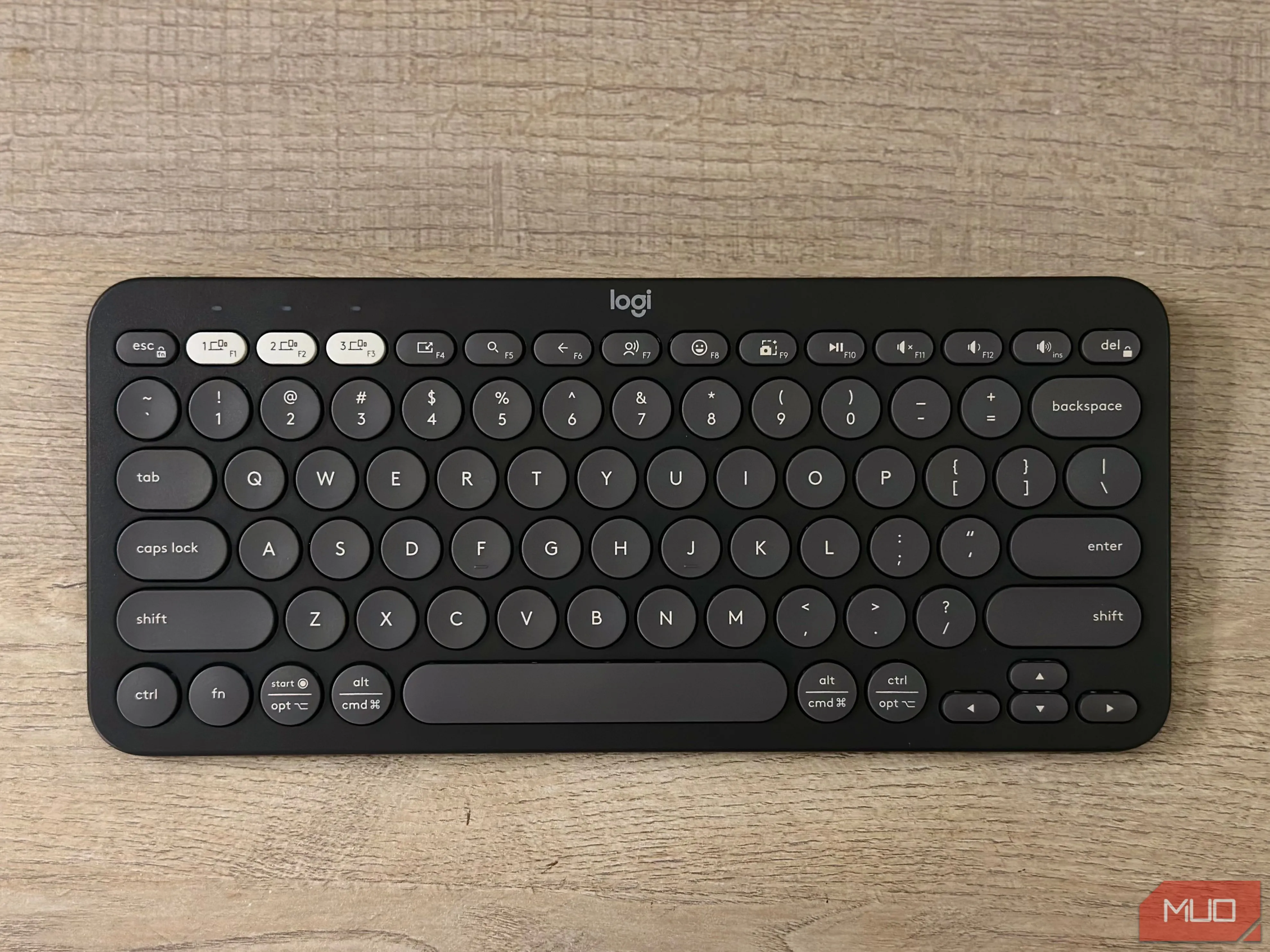 Bàn phím không dây Logitech Pebble Keys 2 K380s màu trắng đặt trên bàn làm việc, thể hiện khả năng tương thích với iPad.