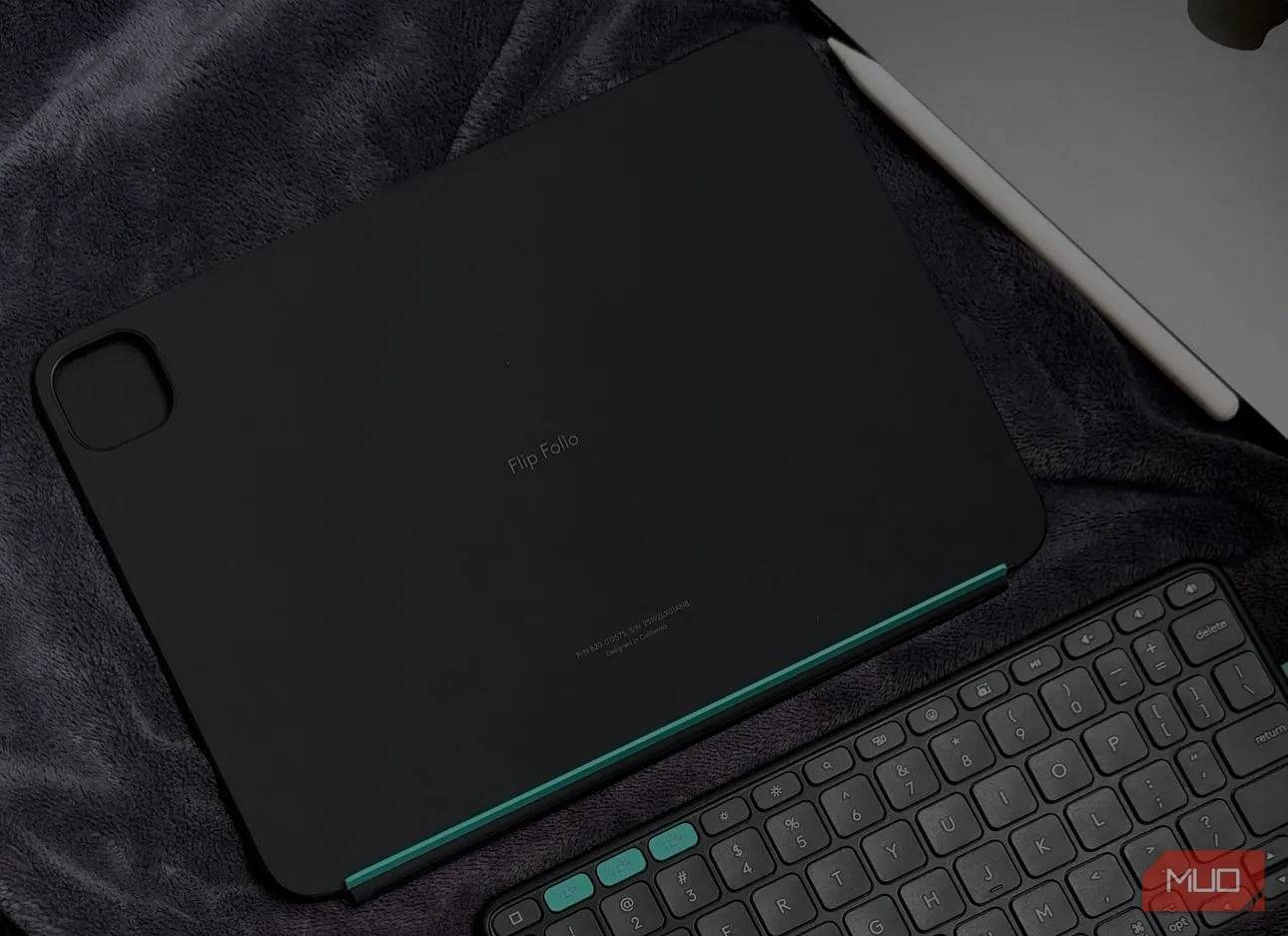 Bàn phím Logitech Flip Folio và iPad đặt cạnh nhau trên chăn bông, thể hiện tính di động