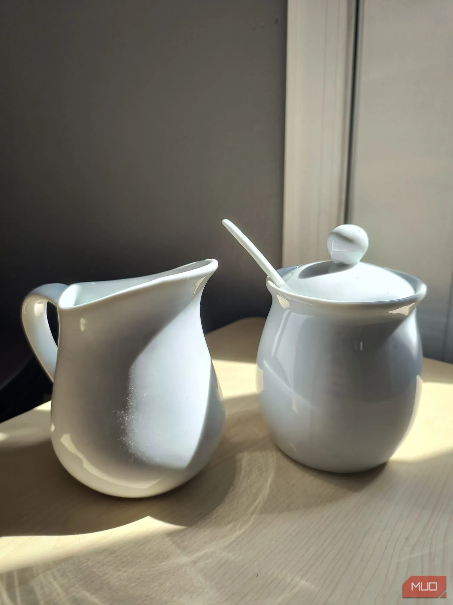 Bộ đựng đường và kem bằng sứ trắng dưới ánh nắng trực tiếp với HDR được bật