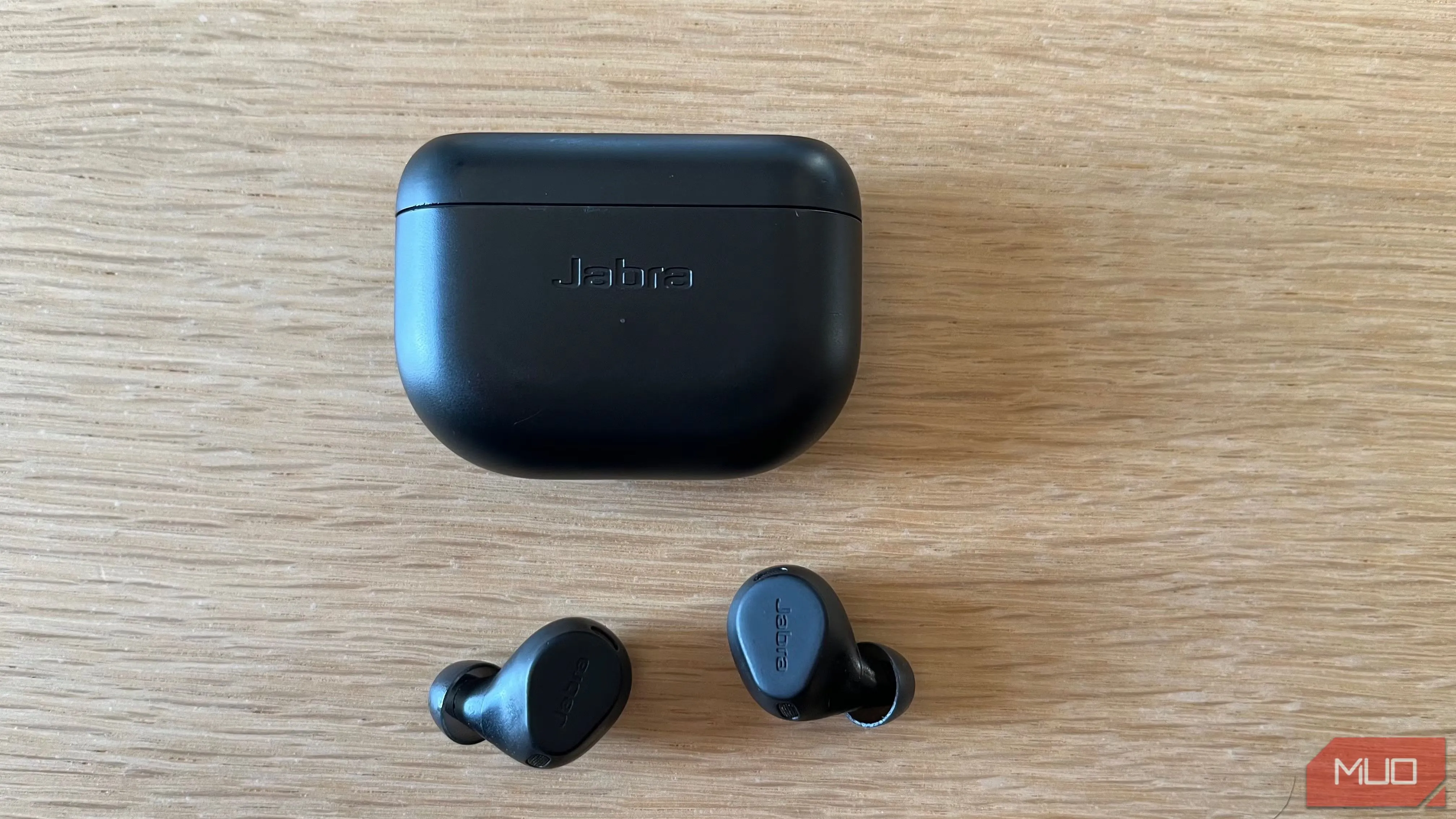 Cặp tai nghe không dây Jabra Elite 8 Active màu đen đặt trên bàn gỗ, biểu trưng cho sự tập trung và giảm tiếng ồn khi làm việc