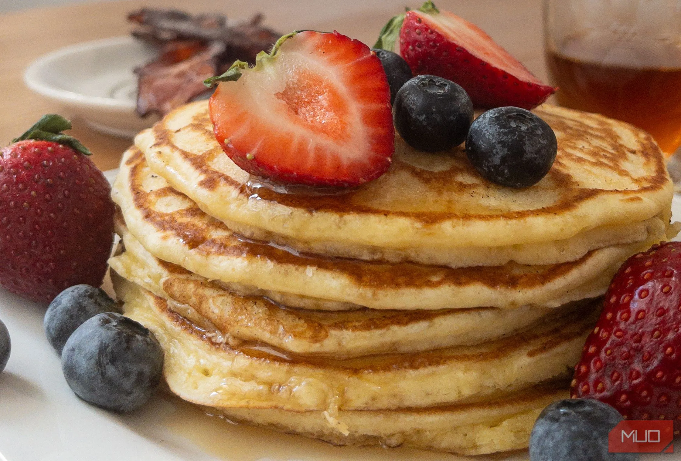 Chồng bánh pancake với xi-rô và trái cây được chụp ở góc độ thấp để tăng sự hấp dẫn