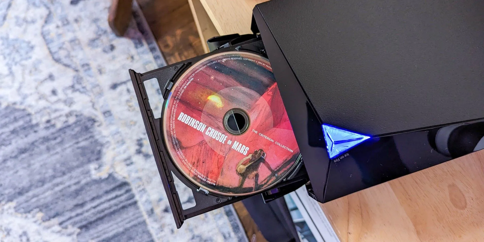 Đầu đĩa DVD hiệu Asus với đĩa DVD đang nằm trong khay, minh họa khả năng kết nối đầu đĩa với màn hình để xem phim.
