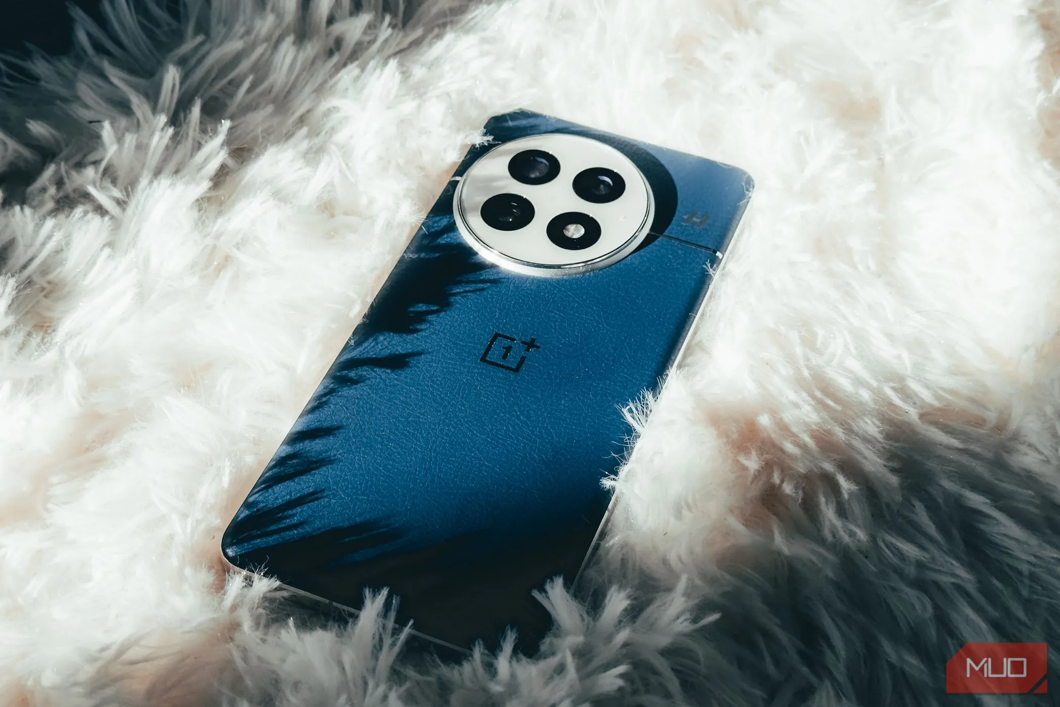 Điện thoại OnePlus 13 với mặt lưng da vegan màu Midnight Ocean trên thảm trắng