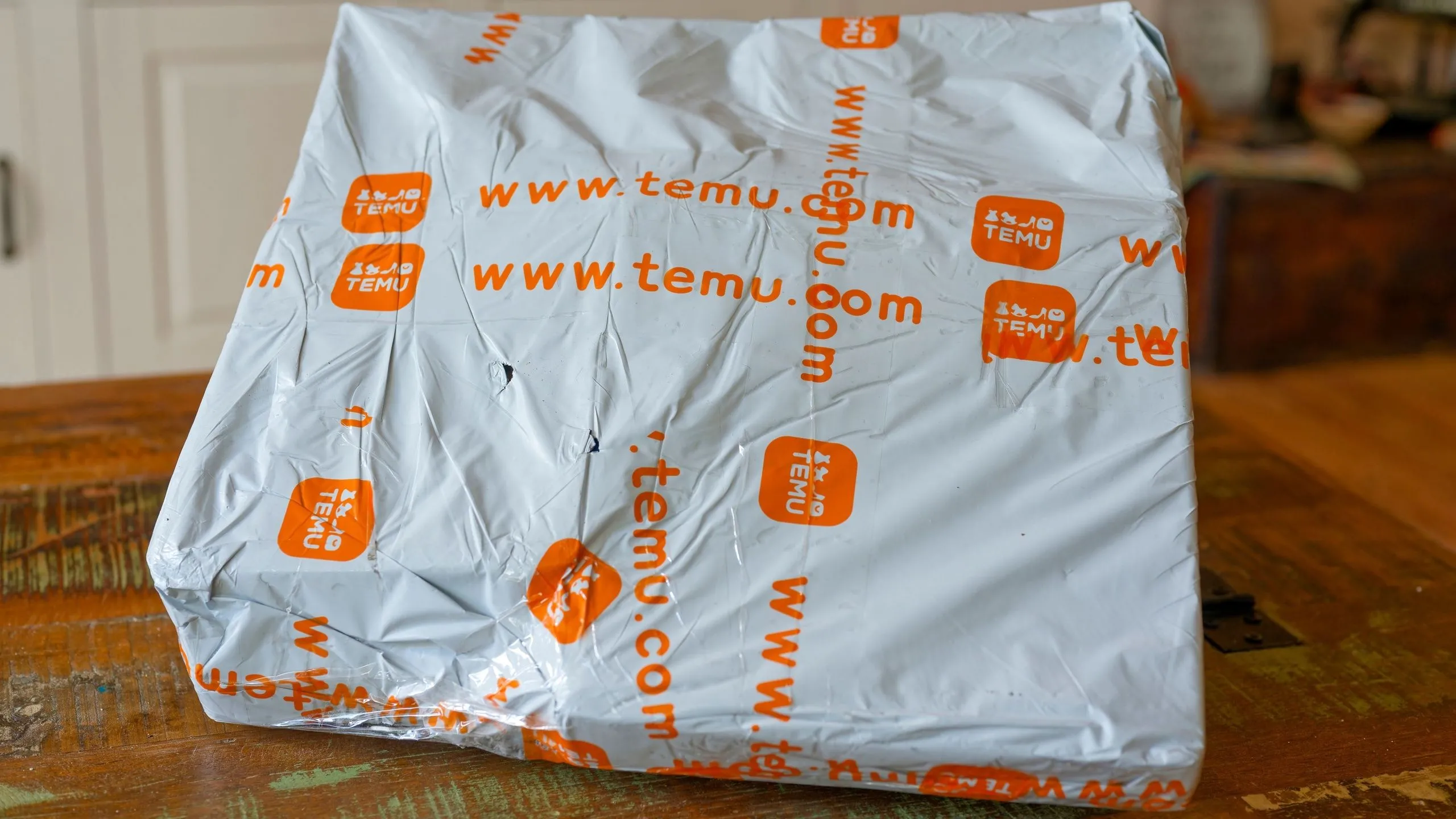 Gói hàng Temu trên bàn, thể hiện sự thay đổi chính sách giá