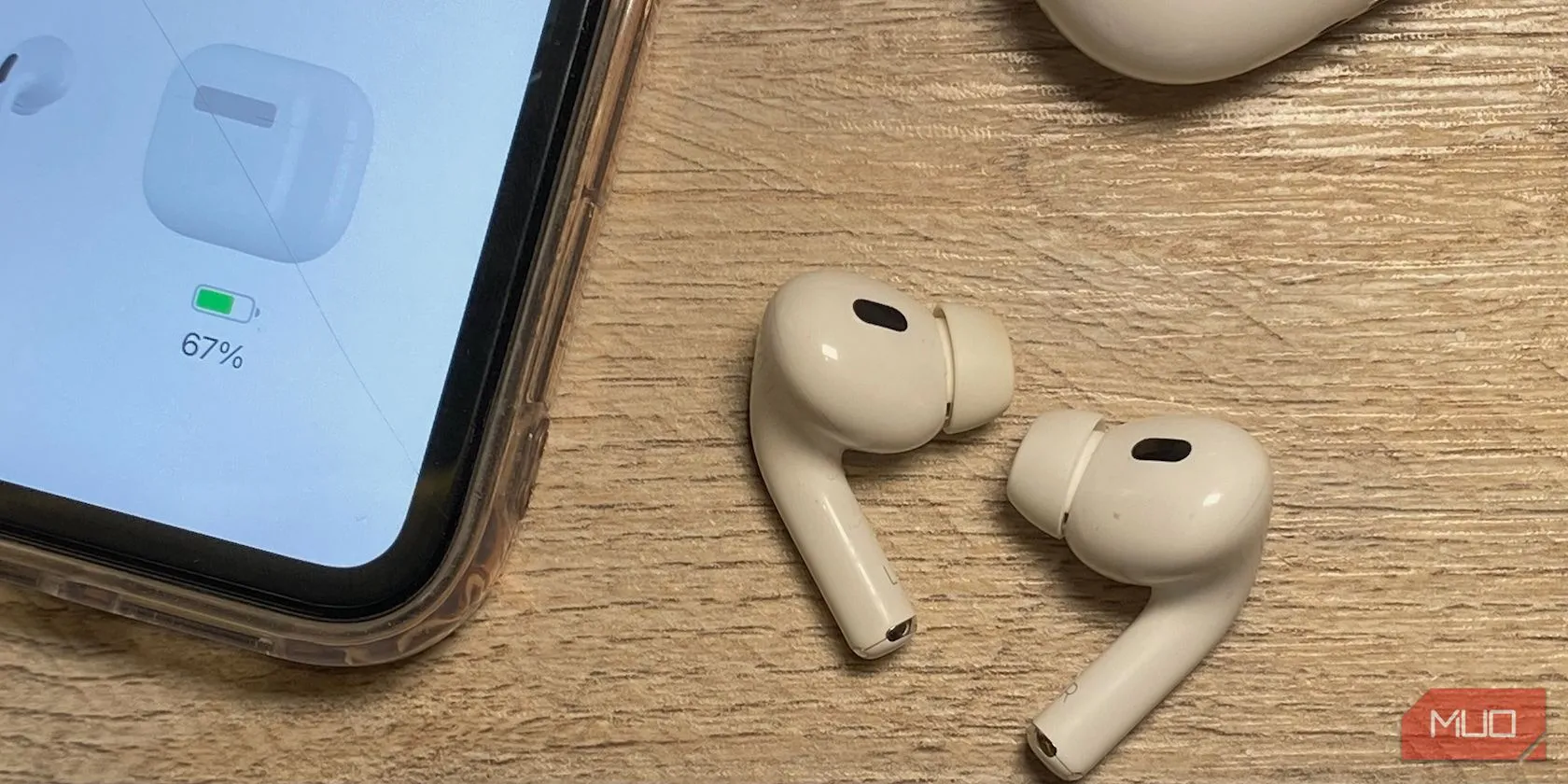 Hình ảnh AirPods đặt trên bàn gỗ cạnh iPhone