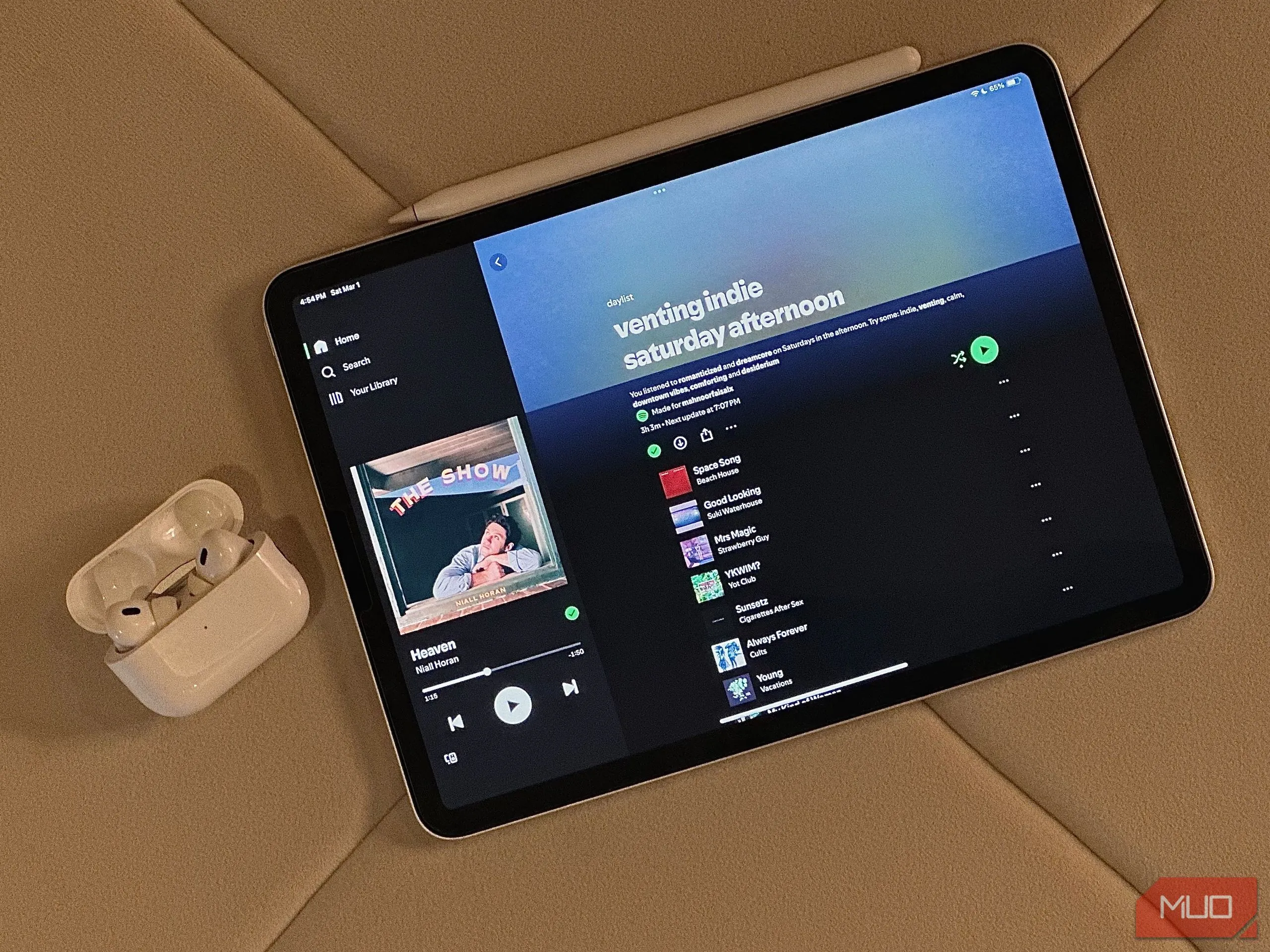 Hình ảnh gốc một chiếc iPad có ứng dụng Daylist và hộp tai nghe AirPods đặt cạnh, chuẩn bị chỉnh sửa