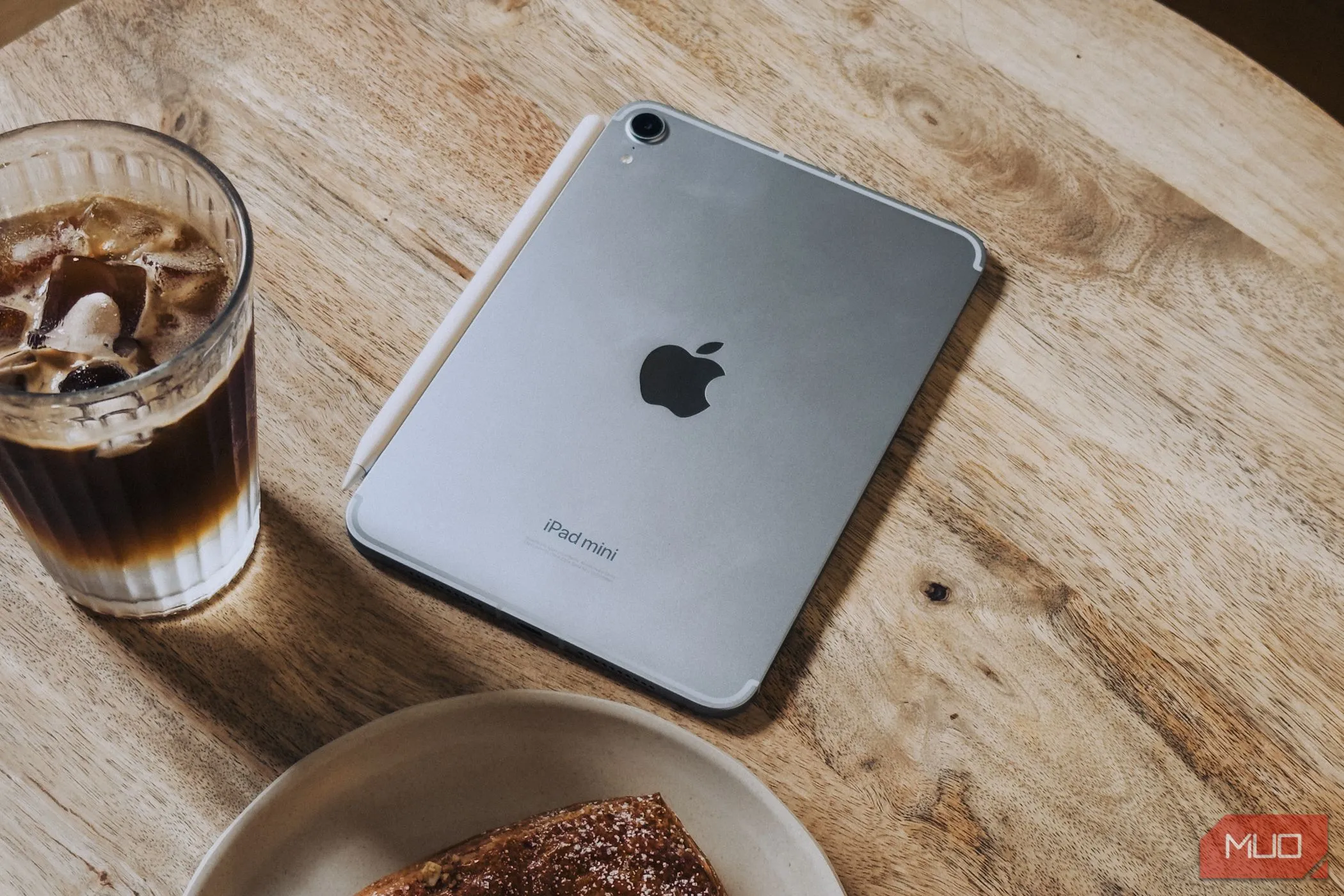 iPad mini (A17 Pro) đặt trên bàn cà phê cạnh đồ ăn, thể hiện sự tiện lợi trong cuộc sống hàng ngày