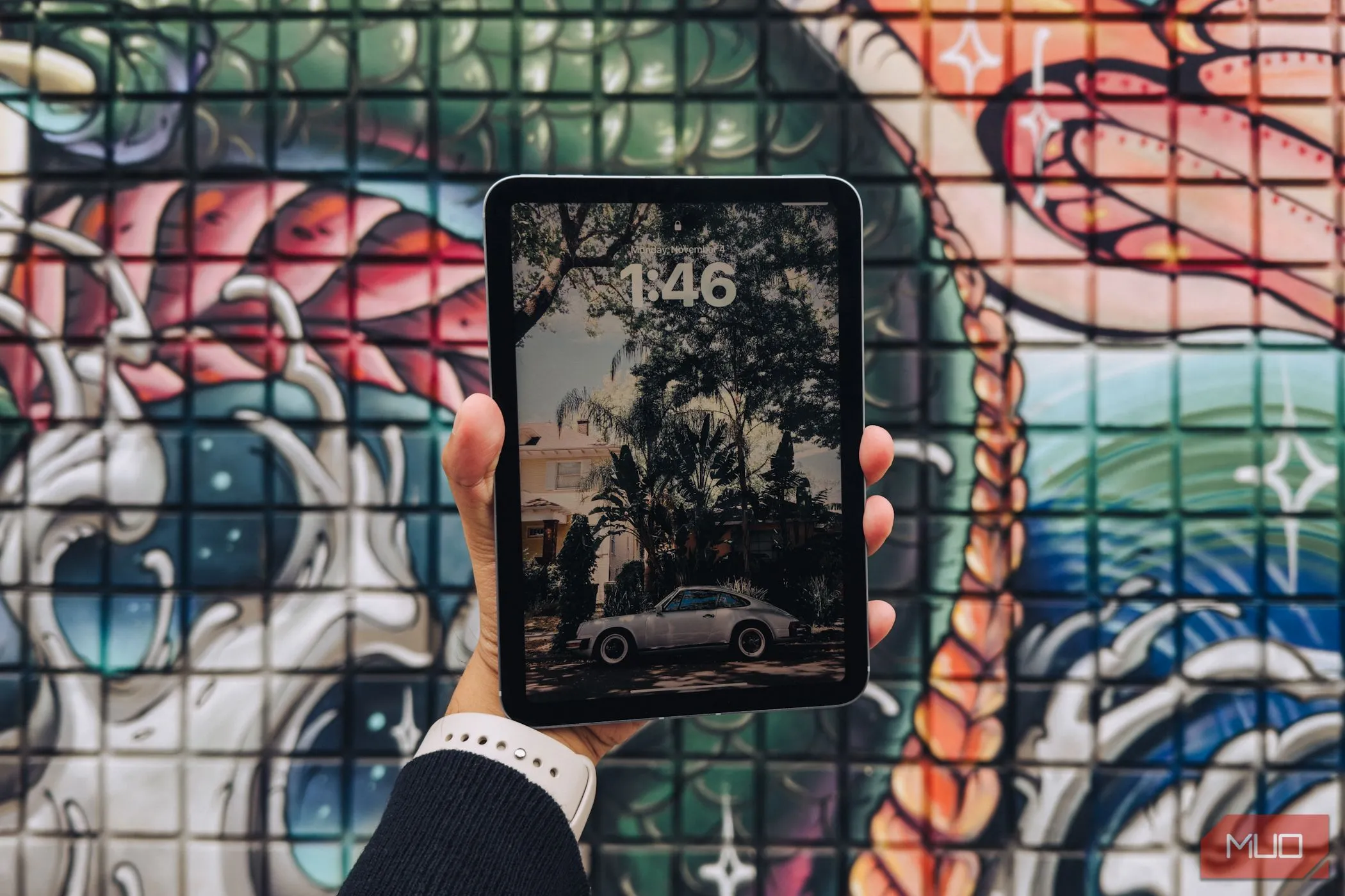 iPad mini (A17 Pro) trong tay, nền graffiti, mặt màn hình