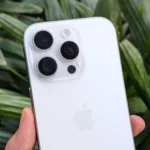 iPhone 16 Pro màu trắng trên tay với khung cảnh cây xanh làm nền, minh họa thiết kế cao cấp và trải nghiệm cầm nắm.