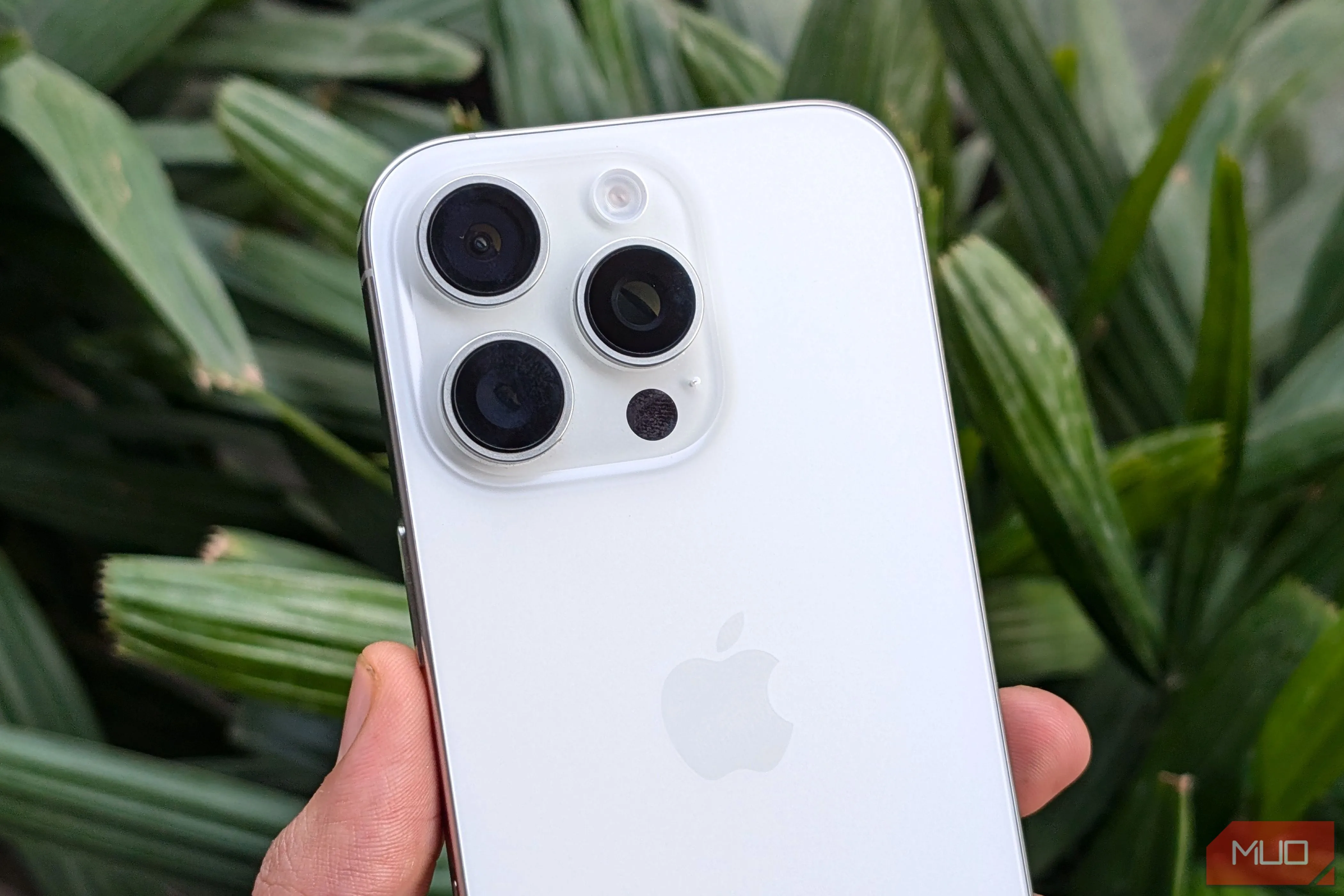 iPhone 16 Pro màu trắng trên tay với khung cảnh cây xanh làm nền, minh họa thiết kế cao cấp và trải nghiệm cầm nắm.