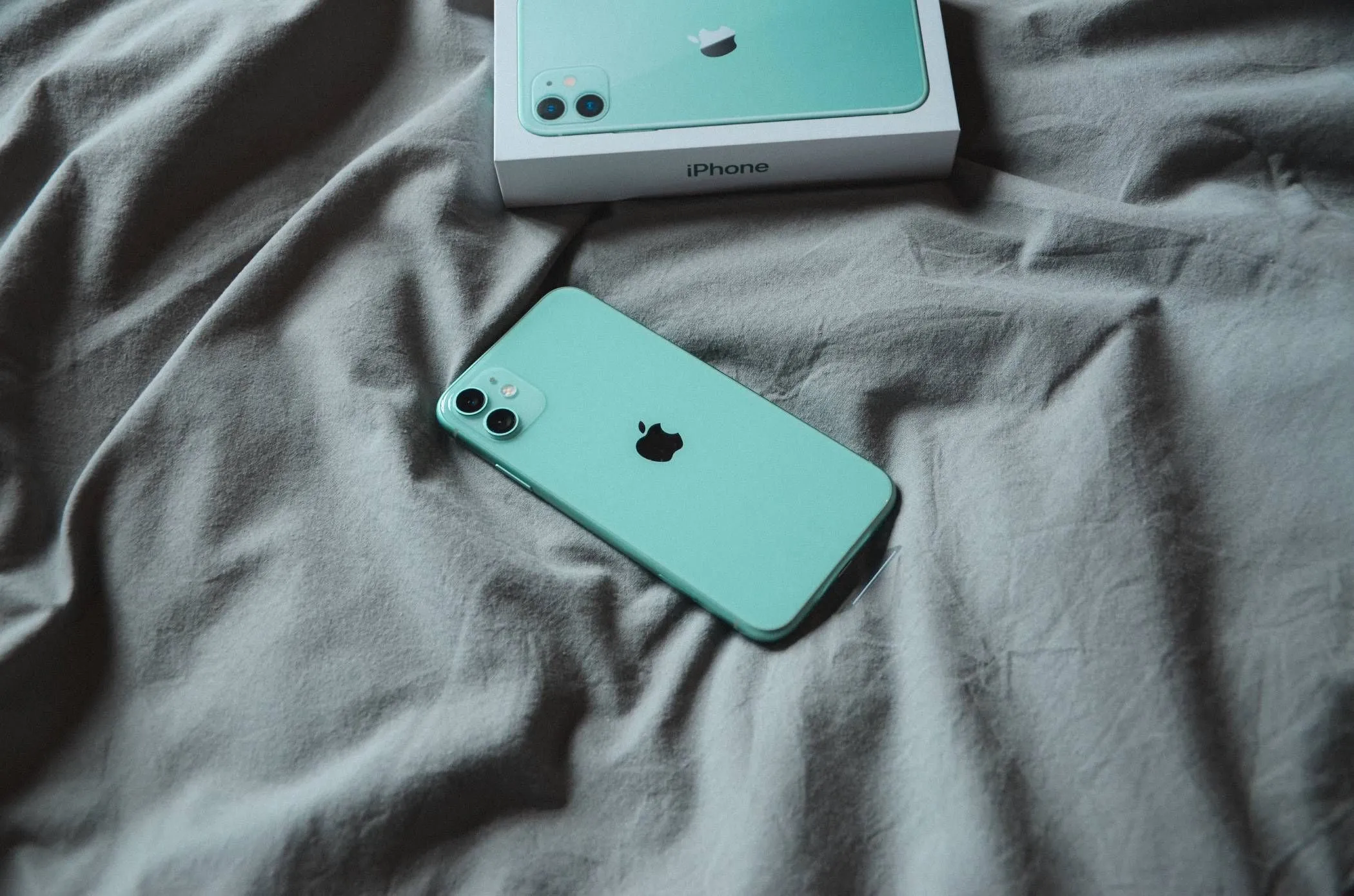 iPhone đang nằm trên chăn ga trải giường trong khi sạc