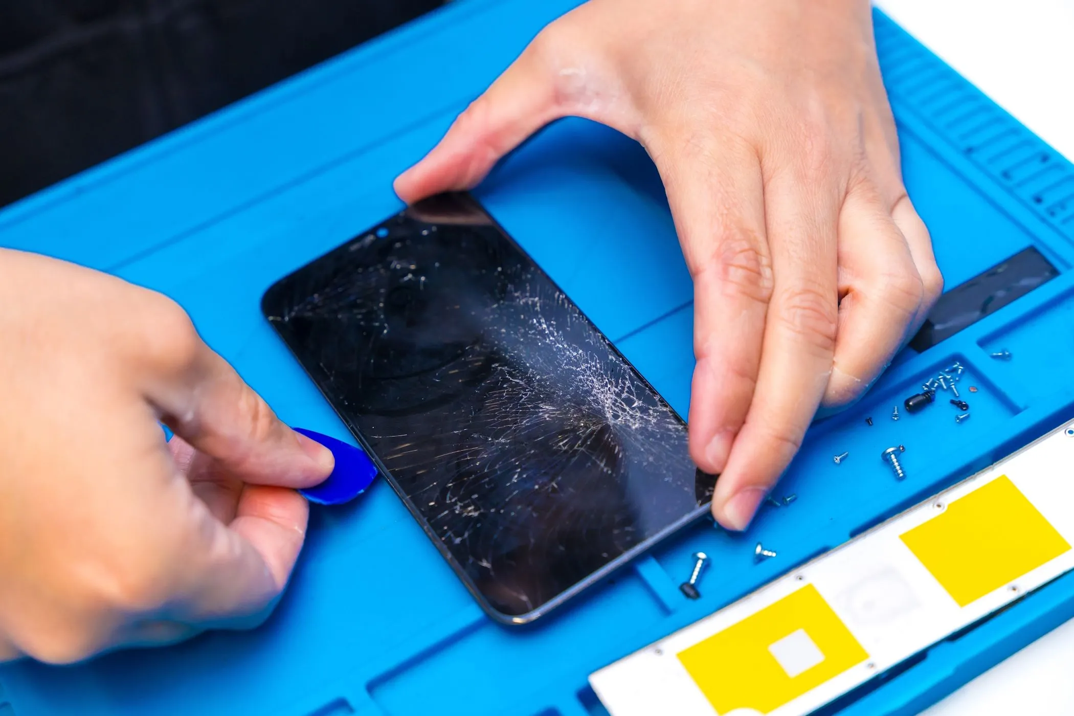 Kỹ thuật viên đang cẩn thận cạy mở smartphone để sửa chữa tại trung tâm bảo hành