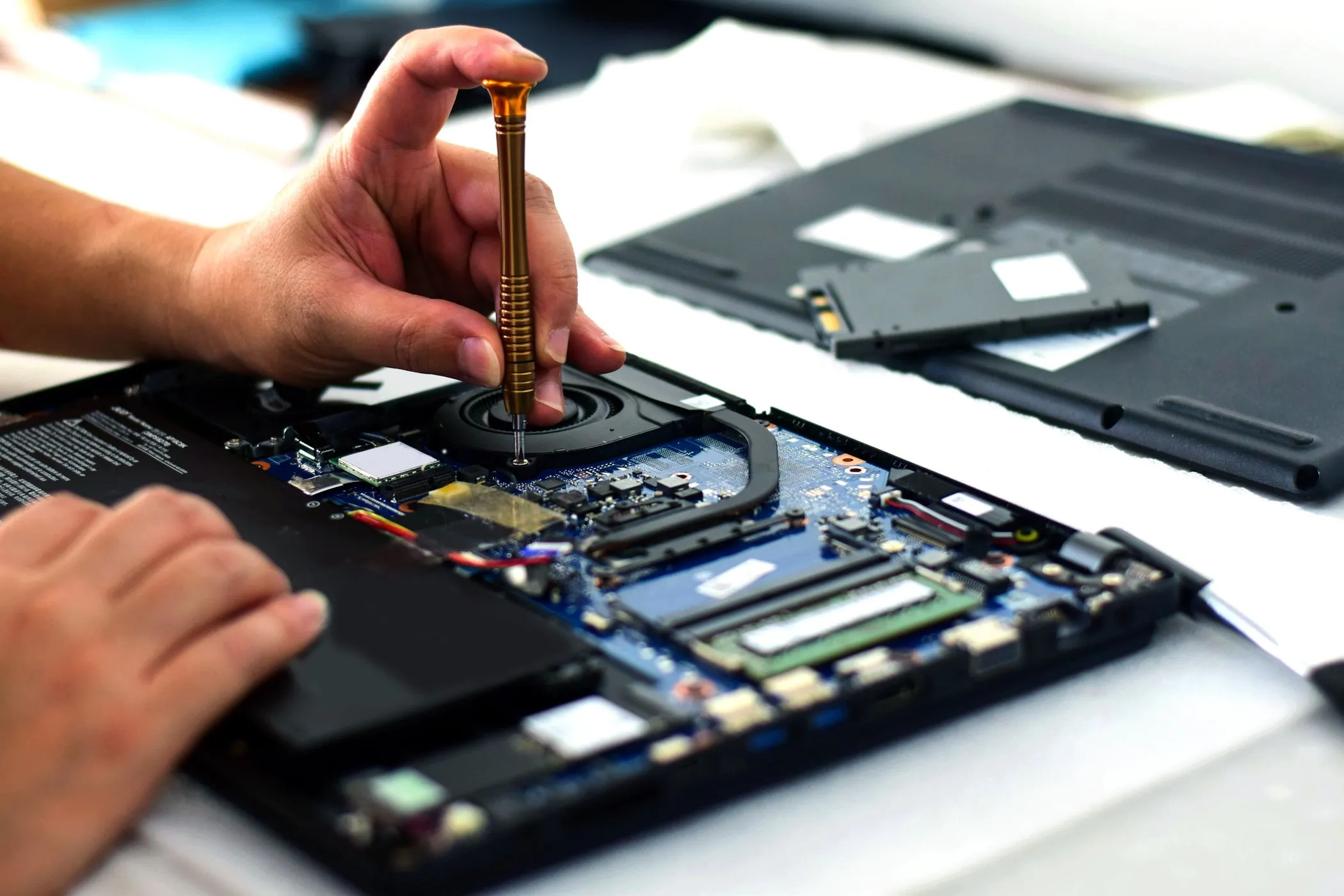 Kỹ thuật viên sửa chữa bo mạch chủ laptop bằng tuốc vít, minh họa khó khăn khi sửa chữa linh kiện hàn chết trên laptop mỏng