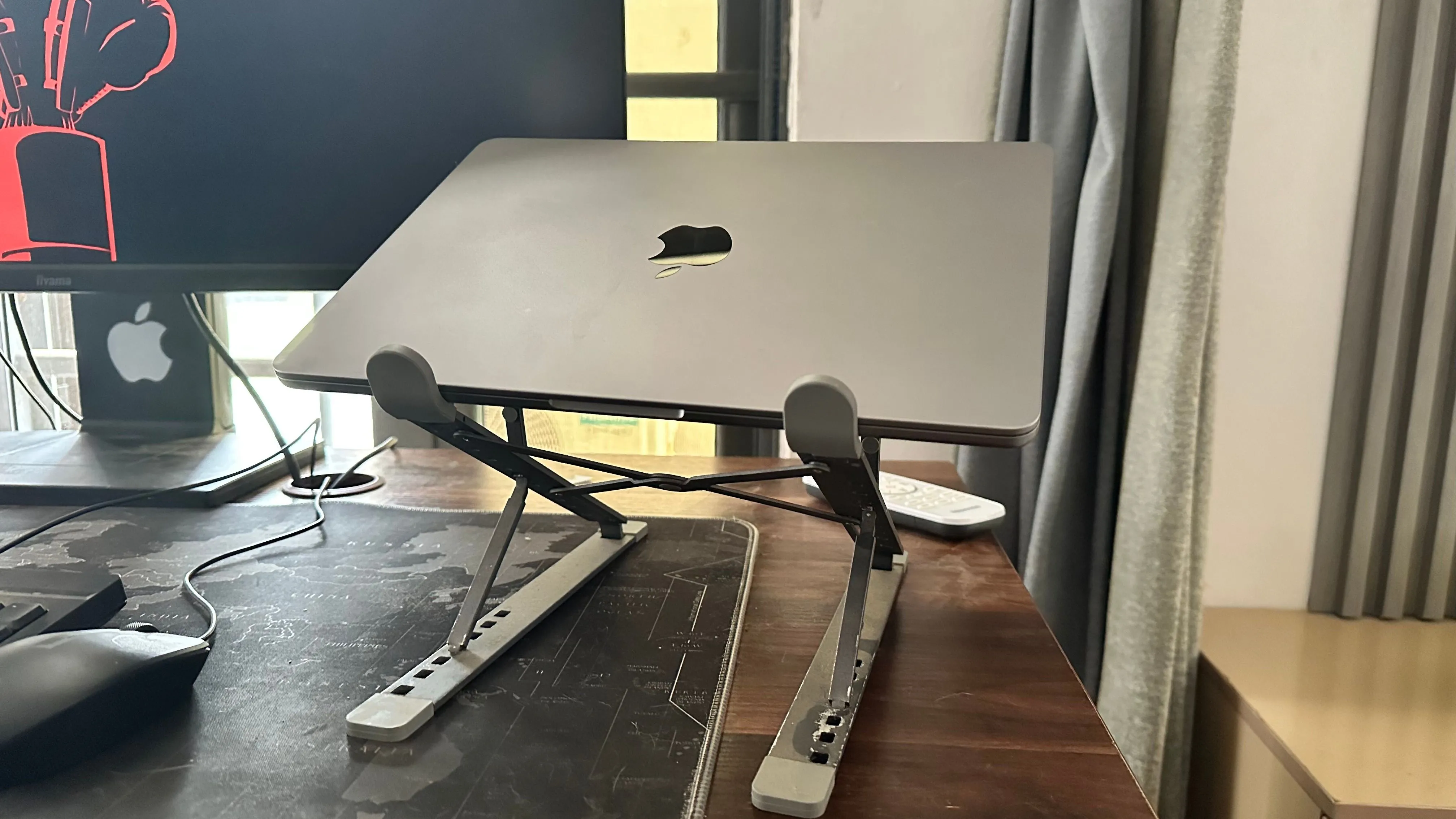 MacBook đặt trên đế tản nhiệt cạnh màn hình ngoài, minh họa vấn đề tản nhiệt và pin