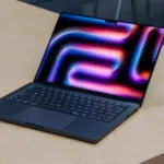 MacBook Pro chạy chip M4 hiển thị giao diện macOS mới trên bàn gỗ