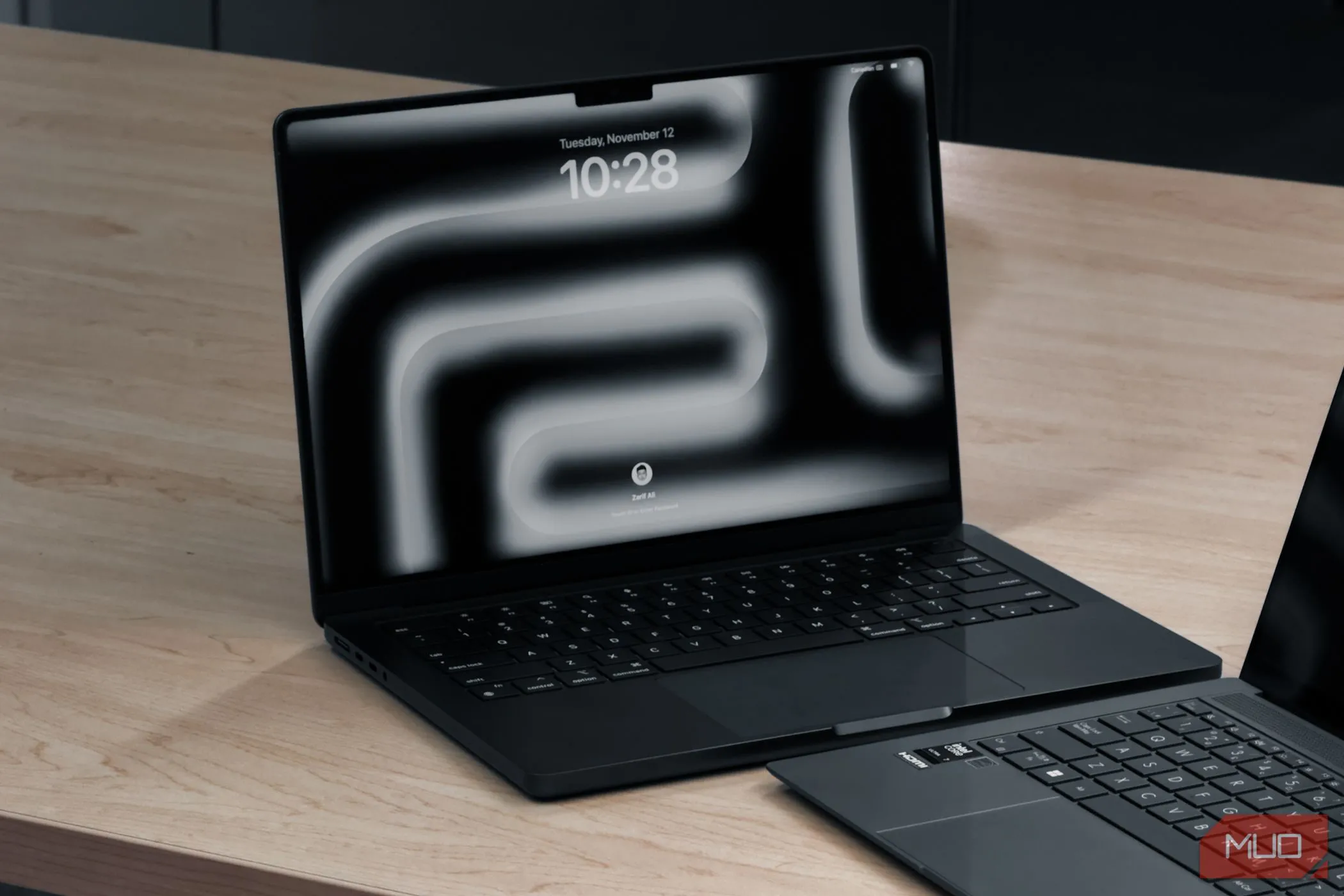 MacBook Pro M4 cùng một laptop khác trên bàn gỗ, minh họa ưu thế về hiệu suất và thiết kế của hệ điều hành macOS.