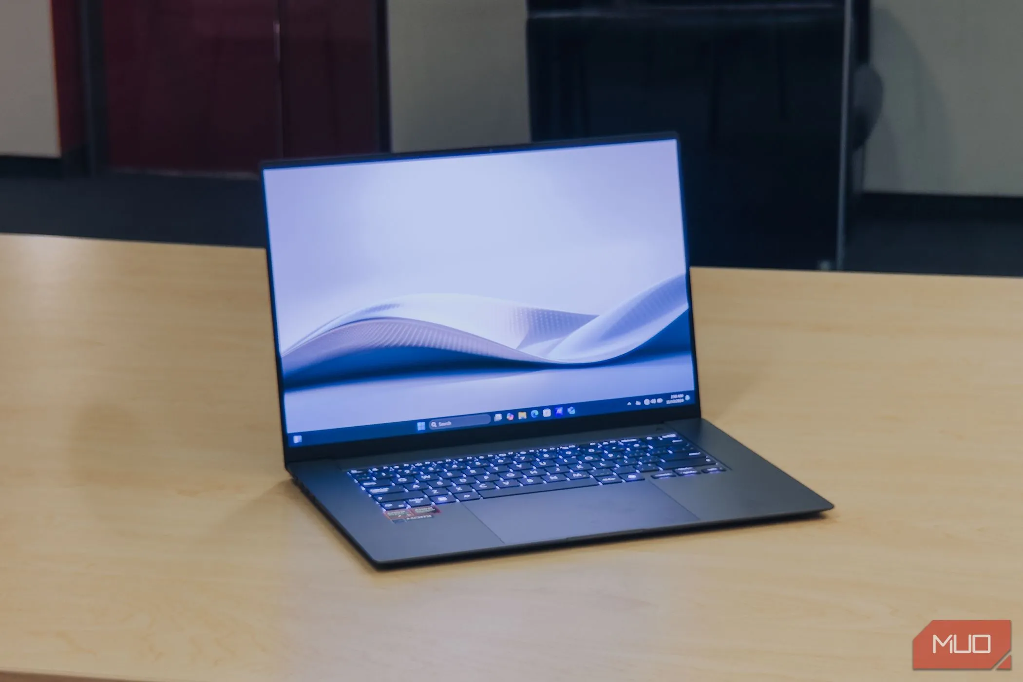 Màn hình ASUS Zenbook S 16 OLED bật ở góc nghiêng trên bàn gỗ