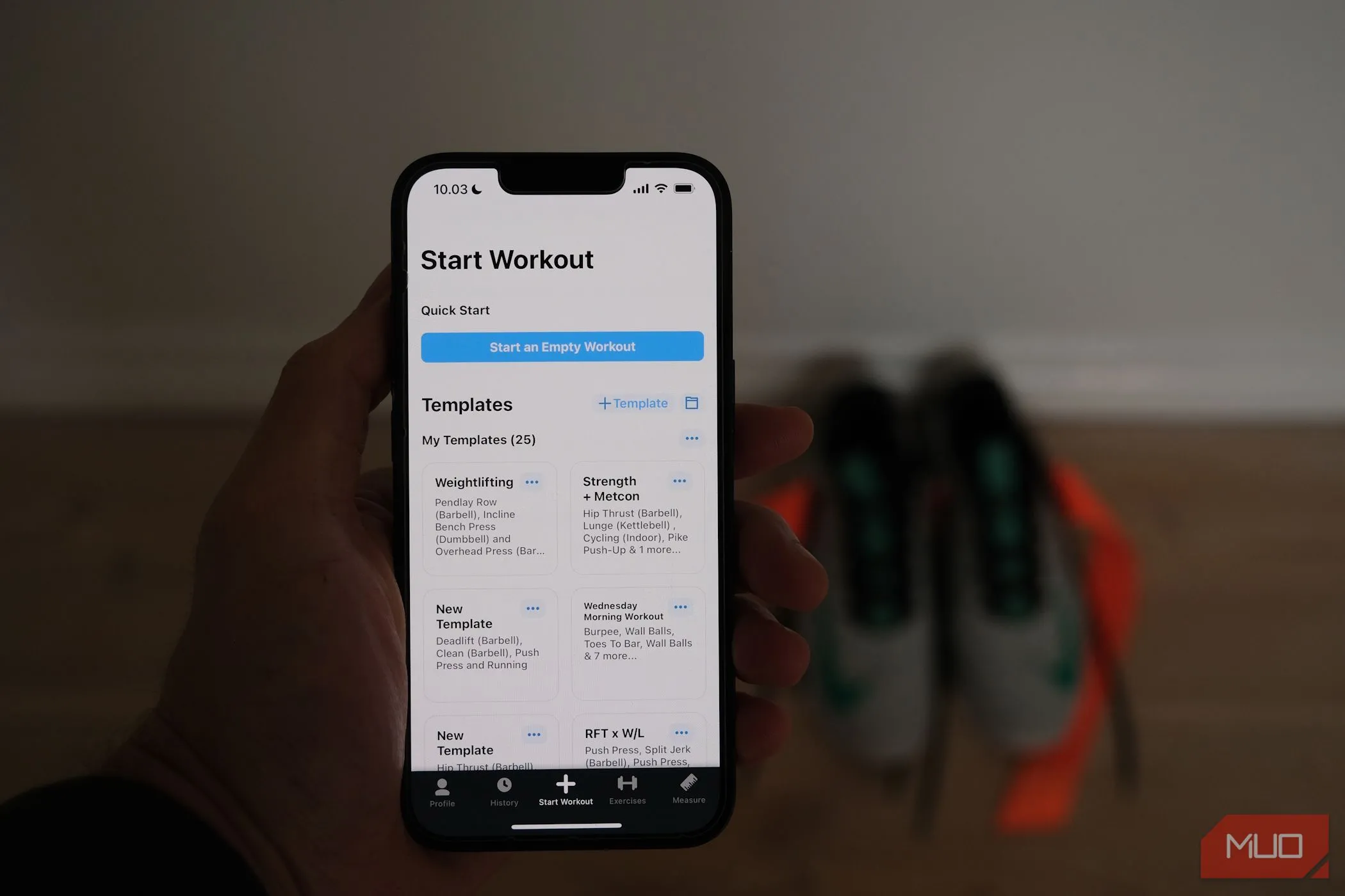 Màn hình iPhone hiển thị ứng dụng theo dõi tập luyện với giày chạy bộ ở hậu cảnh