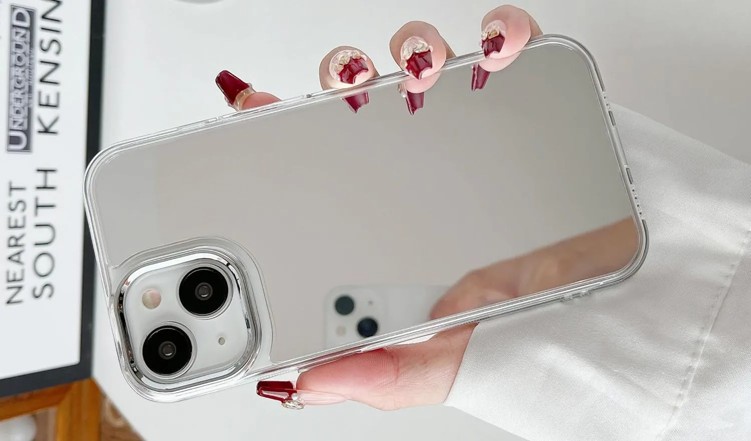 Một bàn tay đang cầm iPhone với ốp lưng phản chiếu mặt gương