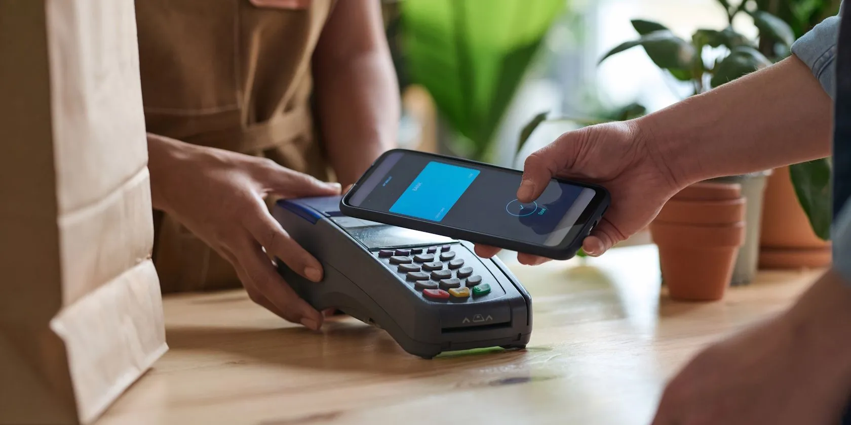 Một người đàn ông đang thực hiện thanh toán không tiếp xúc bằng smartphone tại cửa hàng tạp hóa