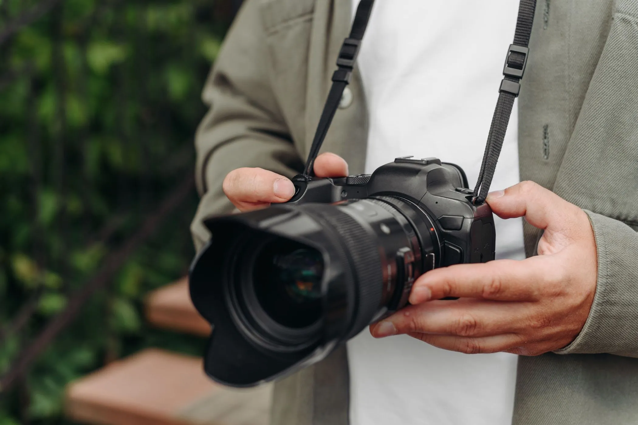Một nhiếp ảnh gia trẻ đang cầm máy ảnh DSLR, thể hiện sự bền bỉ của thiết bị trong môi trường làm việc thực tế