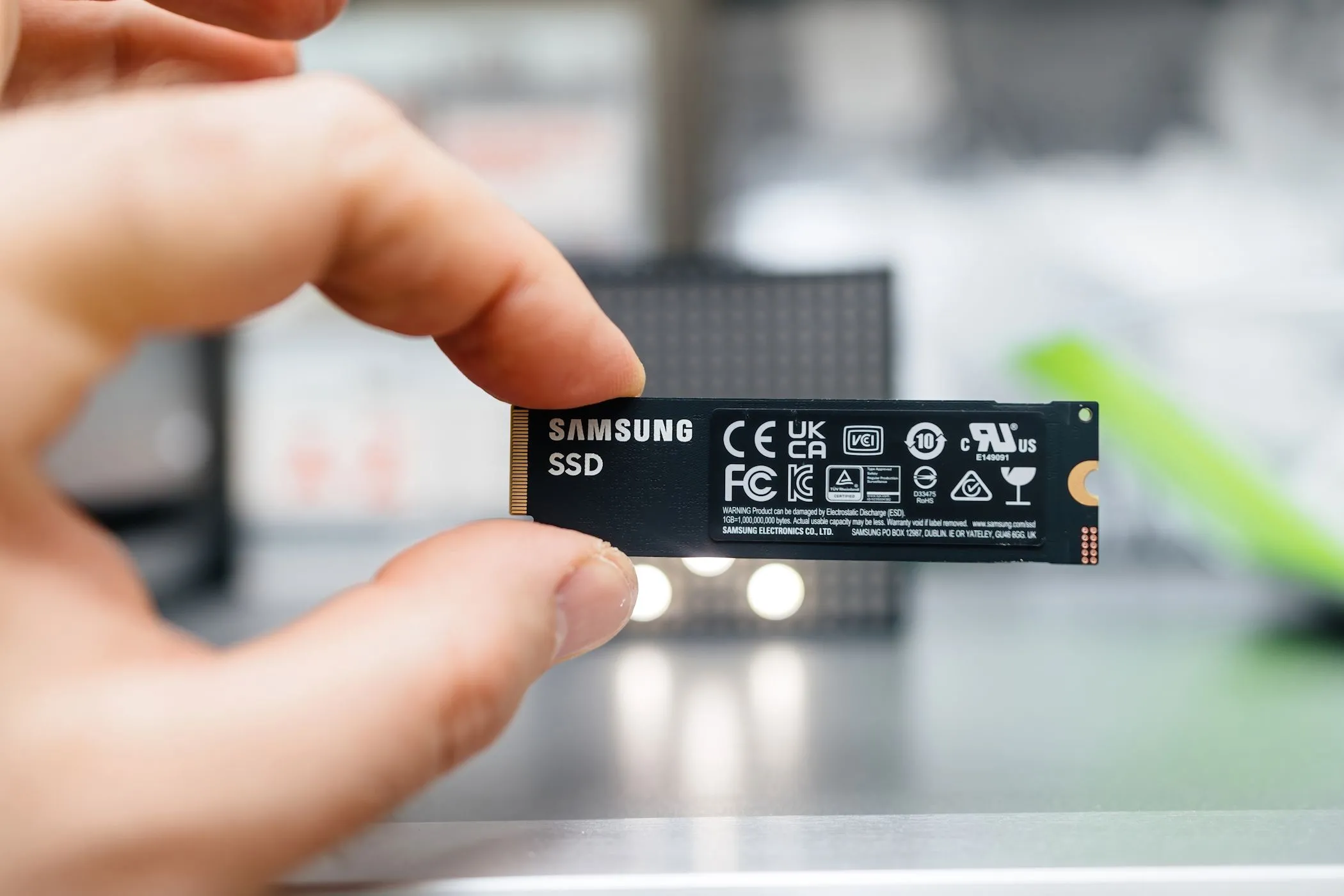 Một ổ cứng SSD Samsung kích thước nhỏ gọn được giữ giữa các ngón tay, biểu tượng cho sự tiện lợi và giá thành phải chăng của SSD hiện đại
