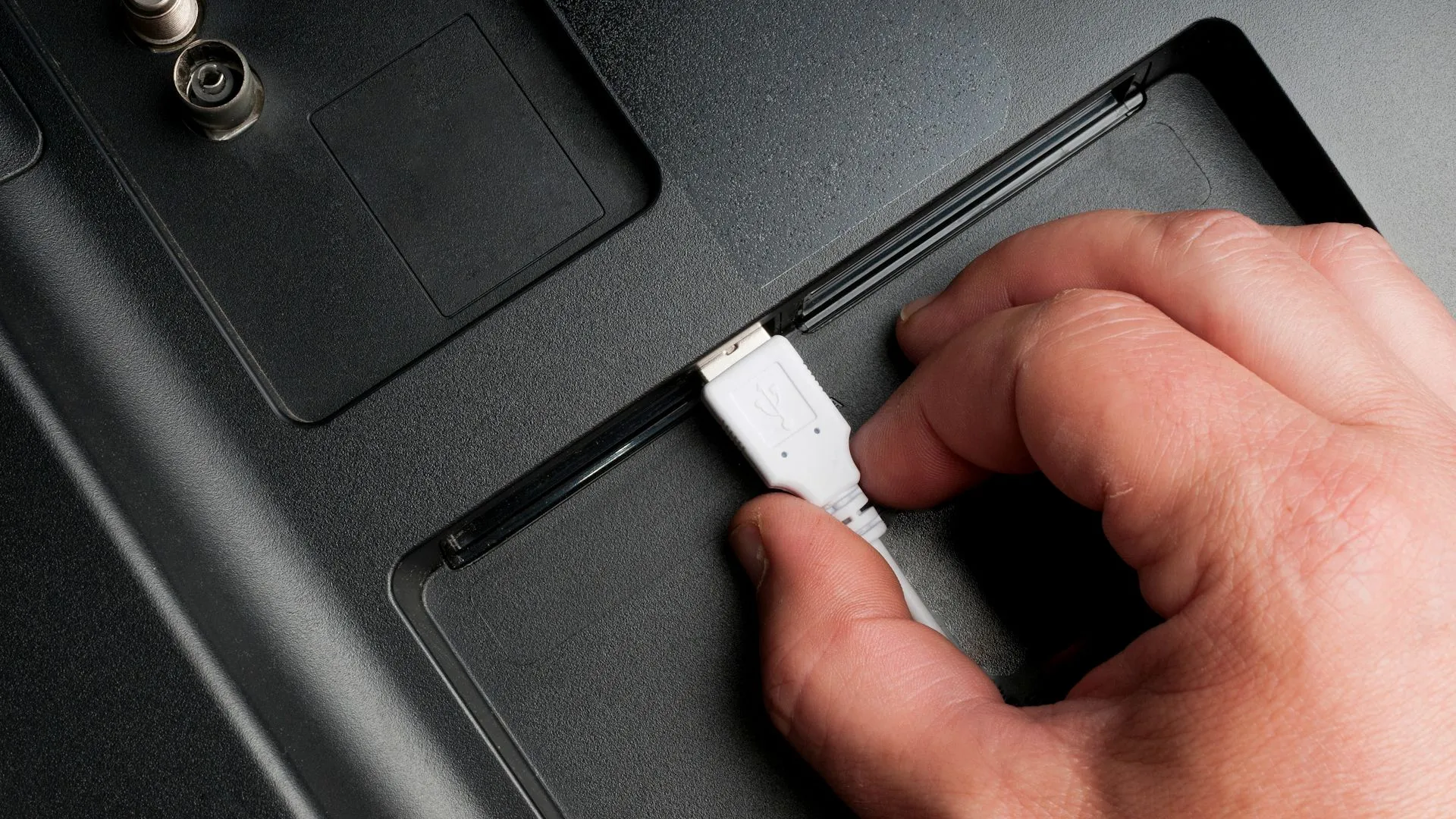Người đàn ông cắm cáp USB Type-A vào cổng TV