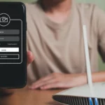Người đàn ông cầm điện thoại cạnh router Wi-Fi đang phát sóng, biểu thị sự tương tác với thiết bị mạng.