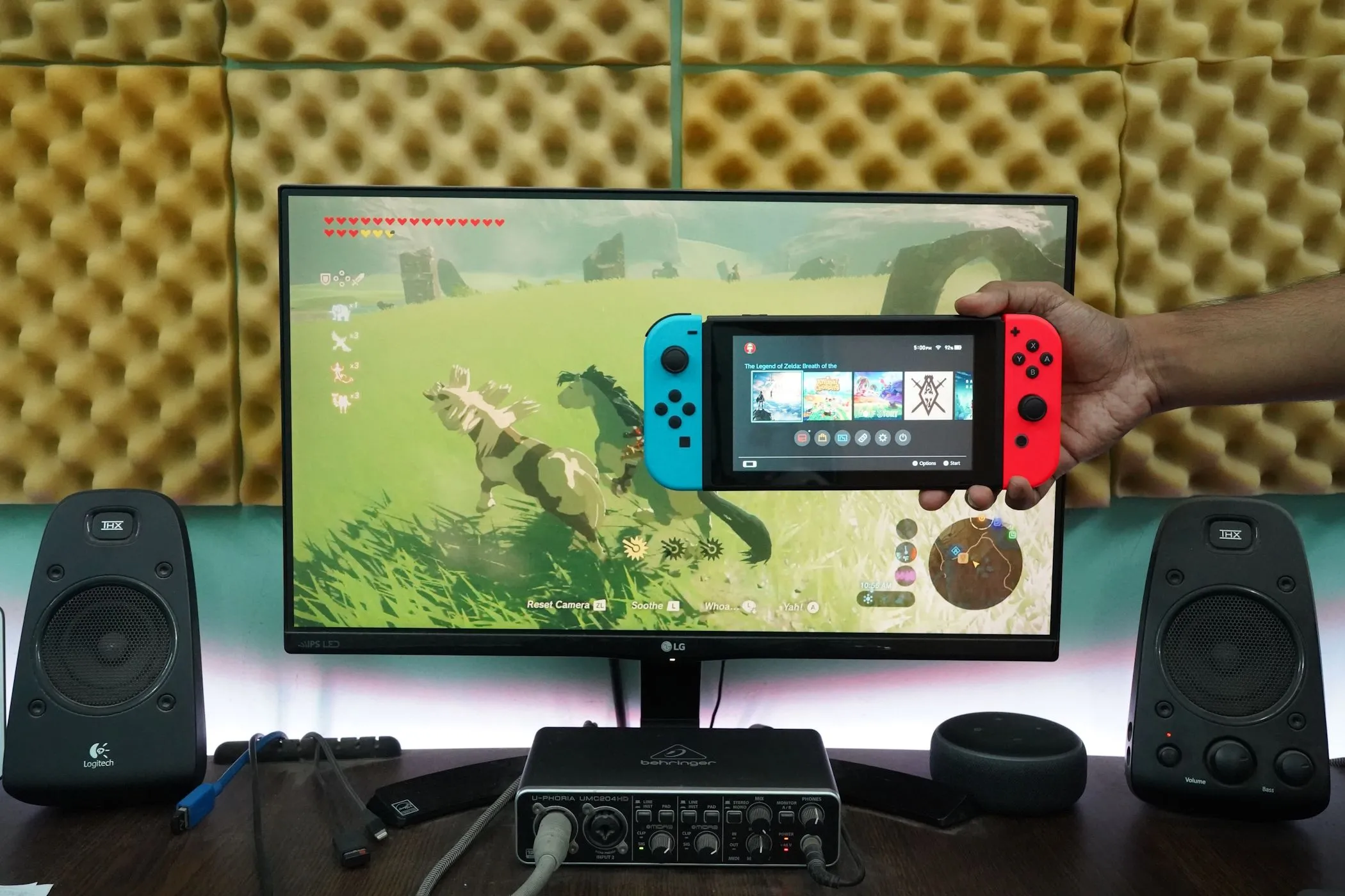 Người đàn ông đang cầm máy chơi game Nintendo Switch trước màn hình máy tính, biểu thị việc kết nối console để trải nghiệm game trên màn hình.