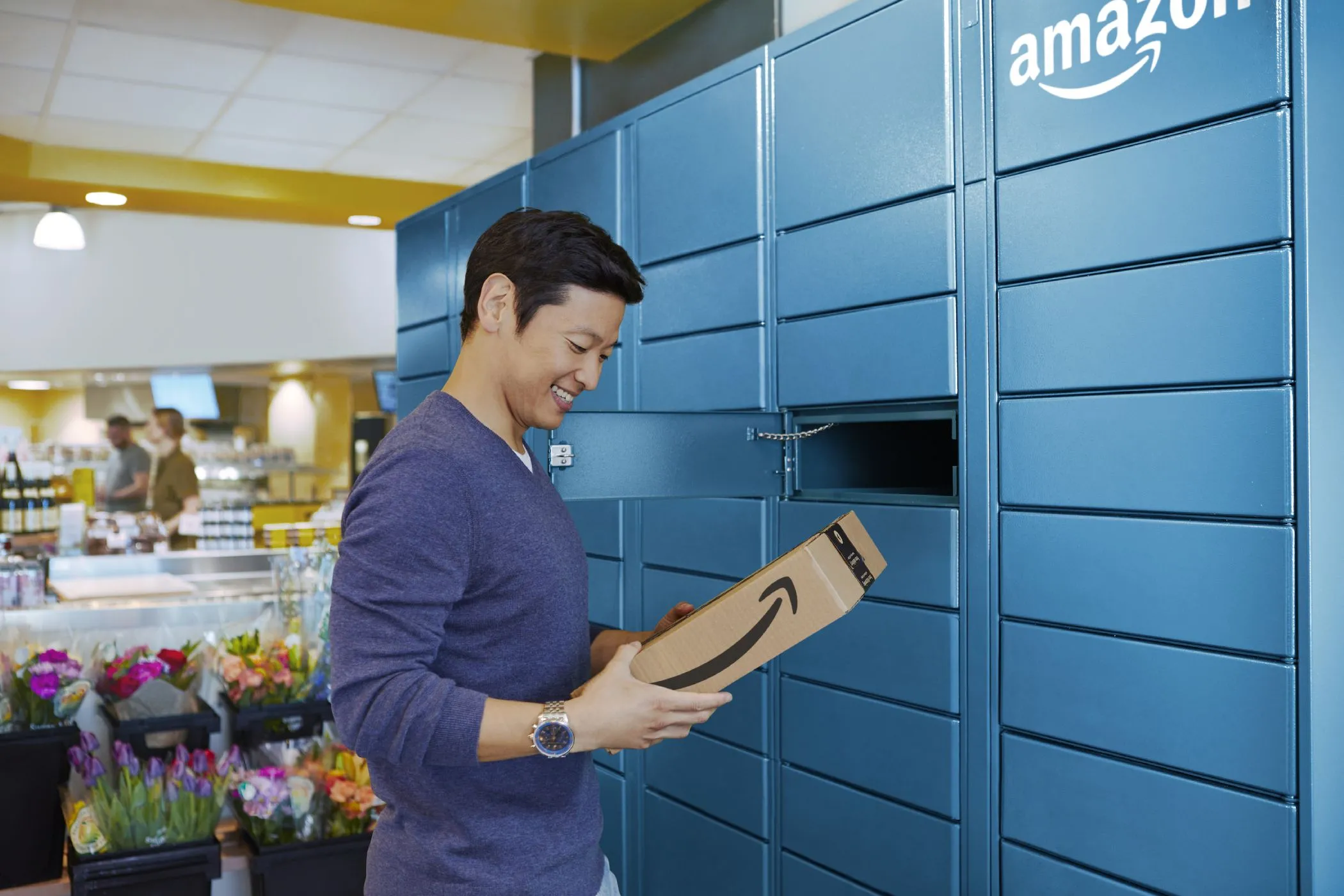 Người đàn ông đang lấy gói hàng từ tủ khóa Amazon