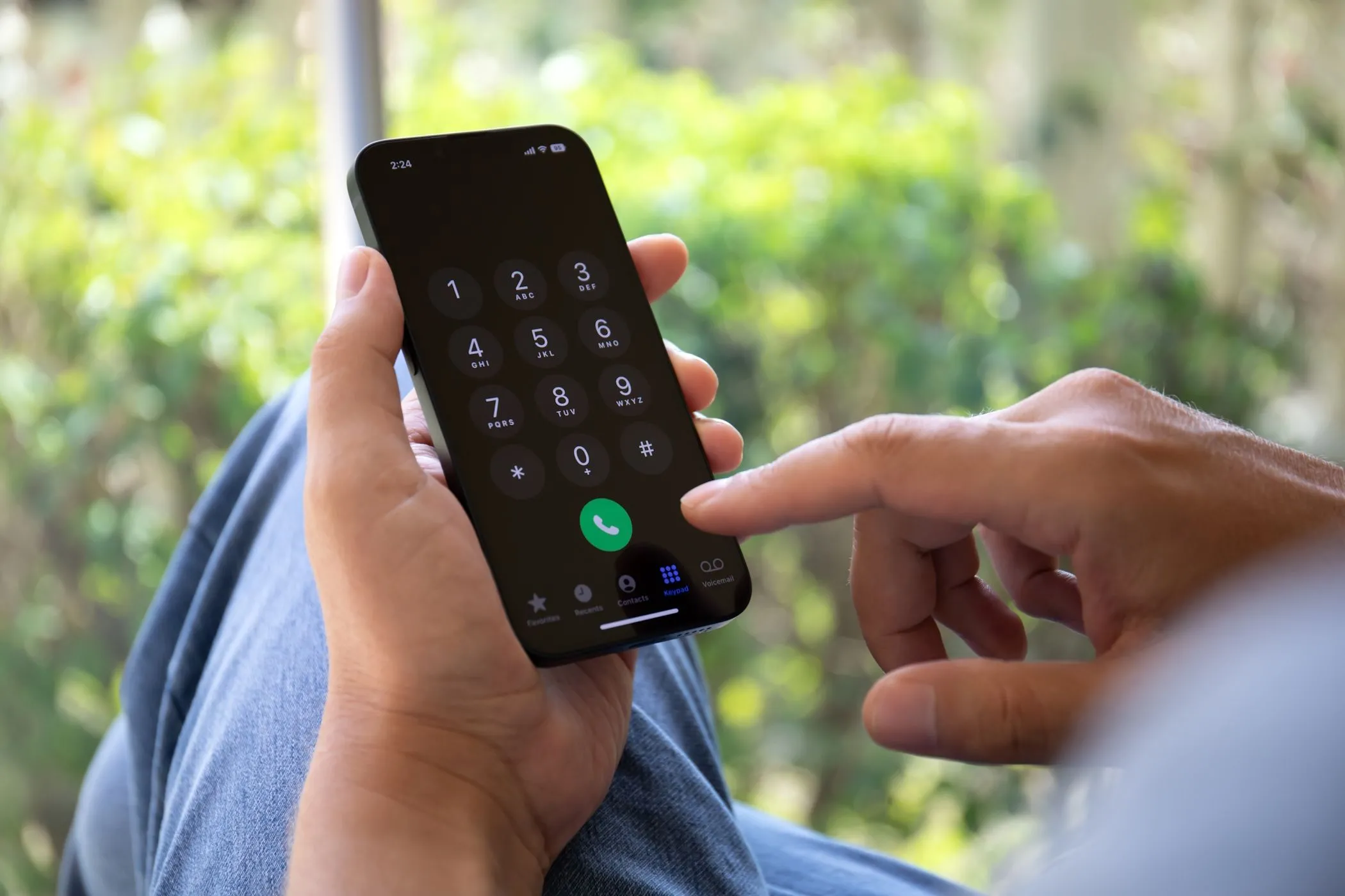 Người đàn ông đang nhập số điện thoại trên iPhone, minh họa sự phụ thuộc của xác thực hai yếu tố SMS vào kết nối di động.