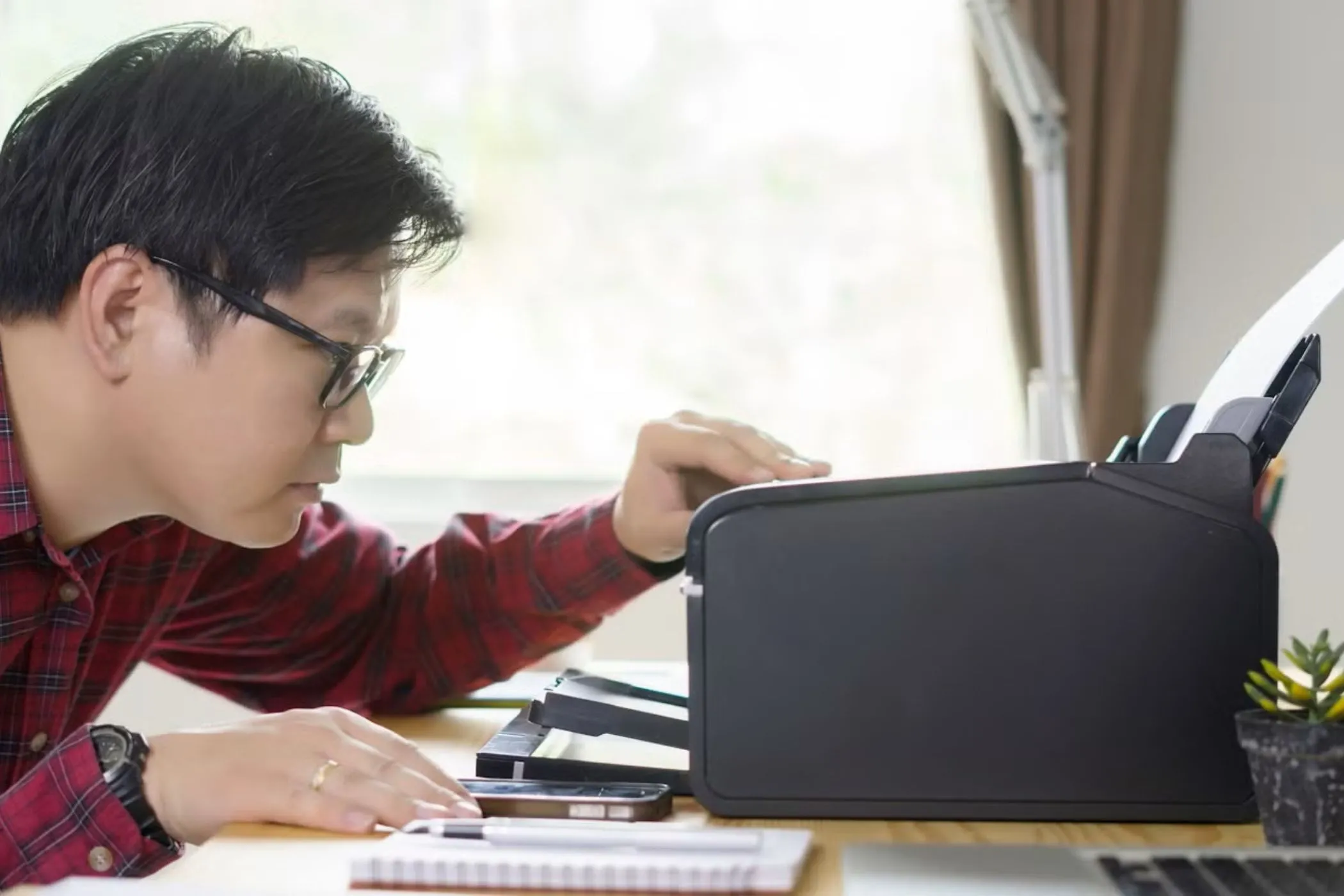 Người đàn ông nhìn vào máy in trên bàn, minh họa vấn đề tương thích thiết bị ngoại vi với Chromebook.