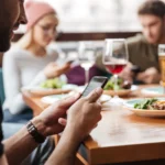 Người đàn ông sử dụng điện thoại tại quán cà phê để tìm kiếm Wi-Fi miễn phí.