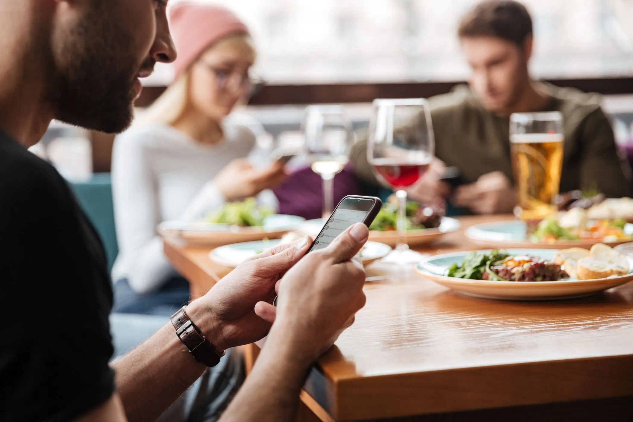 Người đàn ông sử dụng điện thoại tại quán cà phê để tìm kiếm Wi-Fi miễn phí.