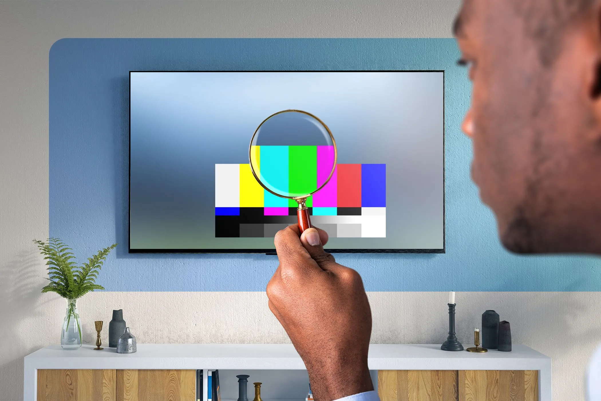 Người đàn ông sử dụng kính lúp kiểm tra chất lượng hiển thị của TV, minh họa sự cần thiết của dải màu rộng (WCG) trong công nghệ HDR.