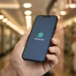 Người dùng cầm điện thoại hiển thị logo WhatsApp, minh họa tính năng chuyển giọng nói thành văn bản