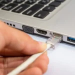 Người dùng đang cắm cáp Ethernet vào cổng mạng trên laptop Windows để kết nối internet an toàn