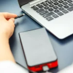 Người phụ nữ cắm cáp USB-C vào laptop từ sạc dự phòng