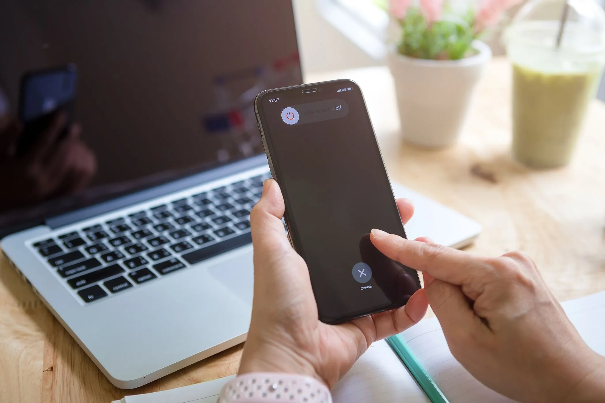 Người phụ nữ đang tắt nguồn iPhone với máy MacBook phía sau