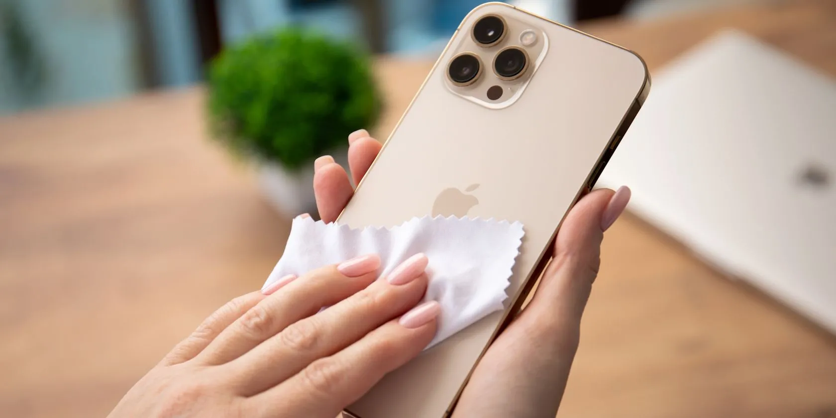 Người phụ nữ đang vệ sinh màn hình iPhone bằng khăn microfiber
