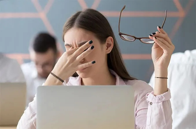 Người phụ nữ dụi mắt do mỏi mắt kỹ thuật số khi dùng Dark Mode