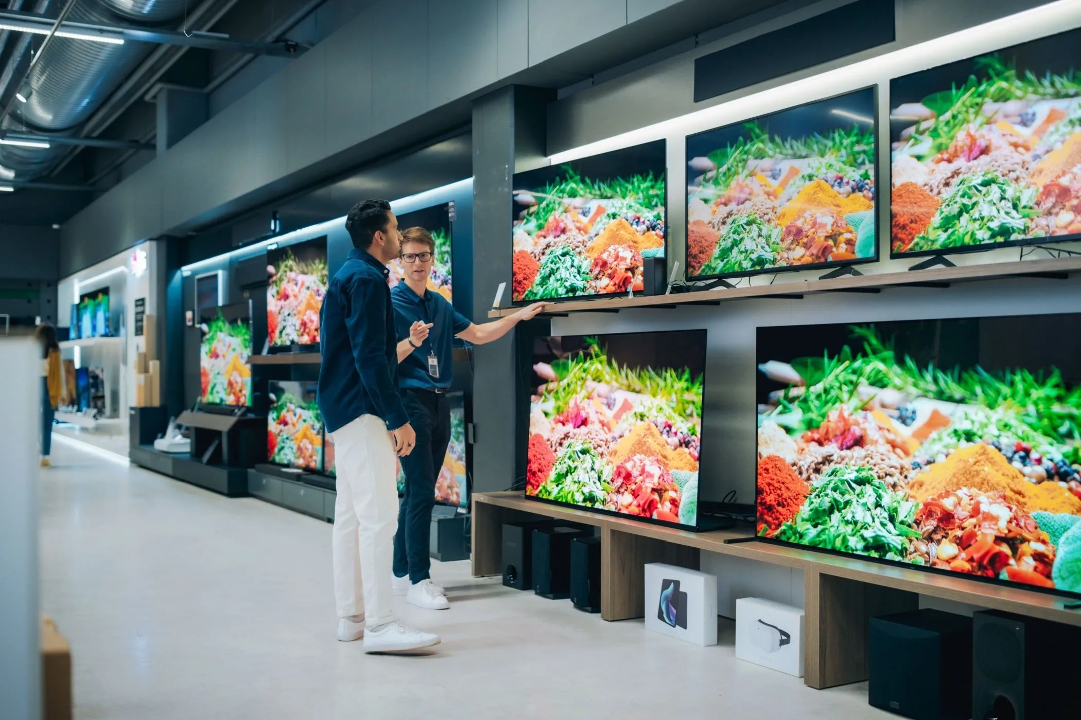 Nhân viên cửa hàng tư vấn TV cho khách hàng, minh họa lợi ích từ ưu đãi thẻ tích điểm.