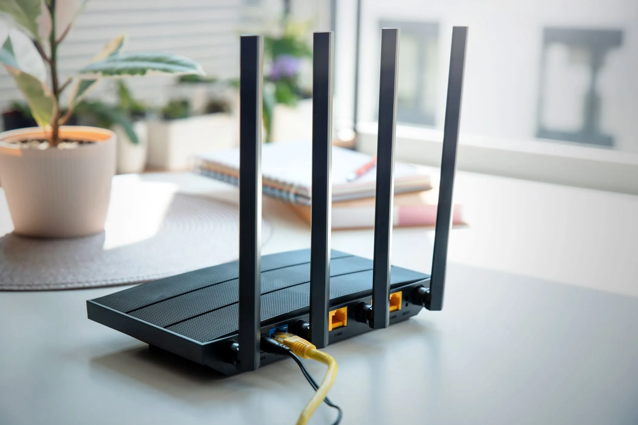 Router Wi-Fi hiện đại với bốn ăng-ten đặt trên bàn, tượng trưng cho thiết bị cần được cập nhật phần mềm định kỳ.