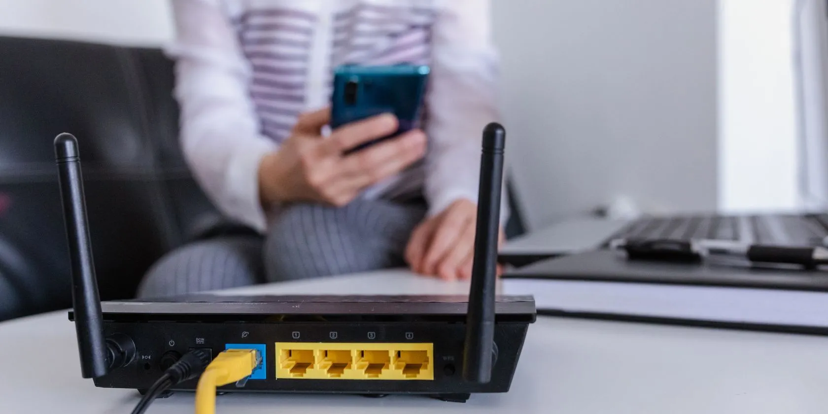 Router Wi-Fi với người dùng ở hậu cảnh, thể hiện mối liên hệ giữa thiết bị mạng và hoạt động của người dùng.