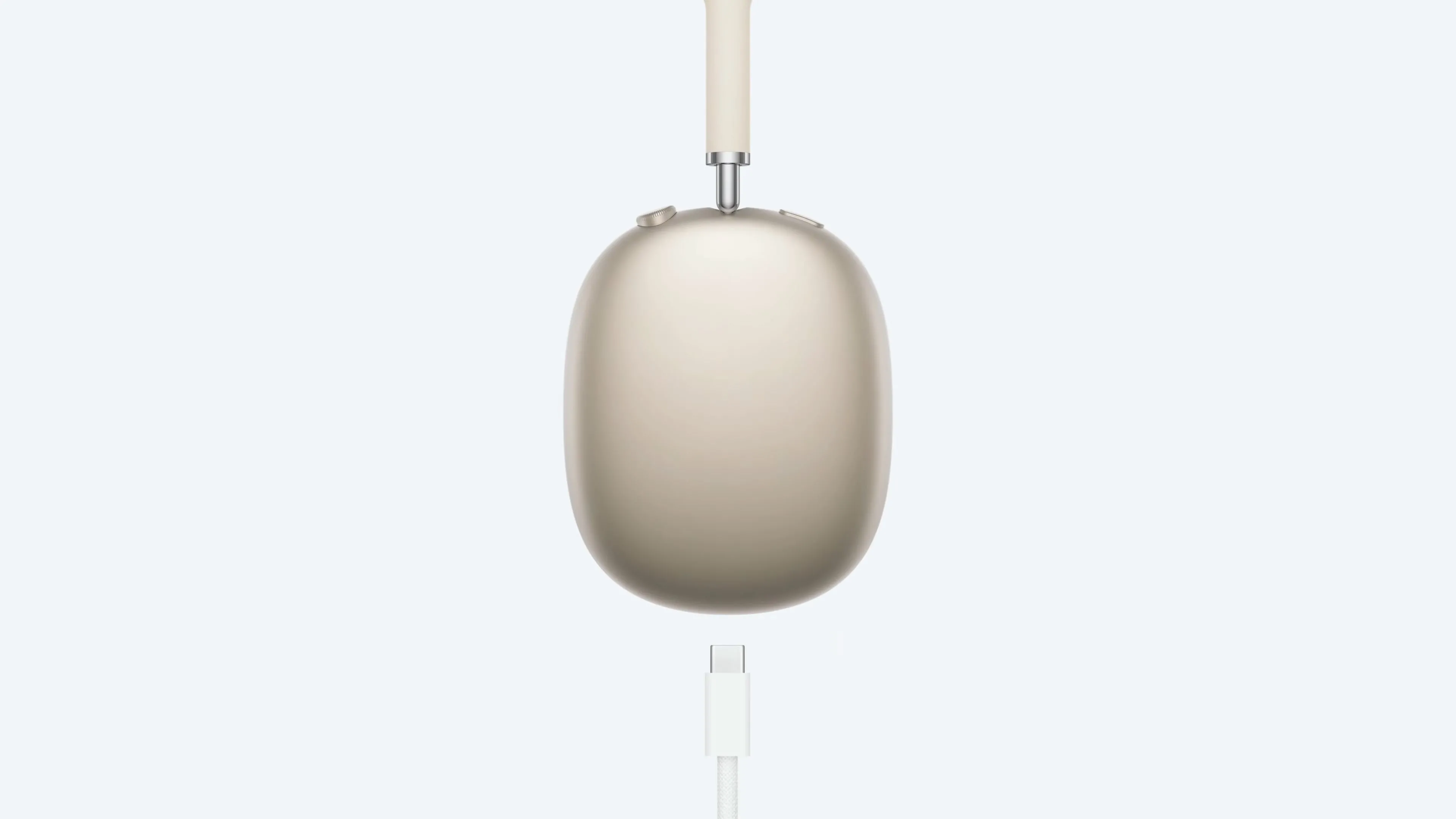 Tai nghe AirPods Max màu Starlight được kết nối với cáp USB-C, minh họa việc không thể vừa sạc vừa sử dụng.