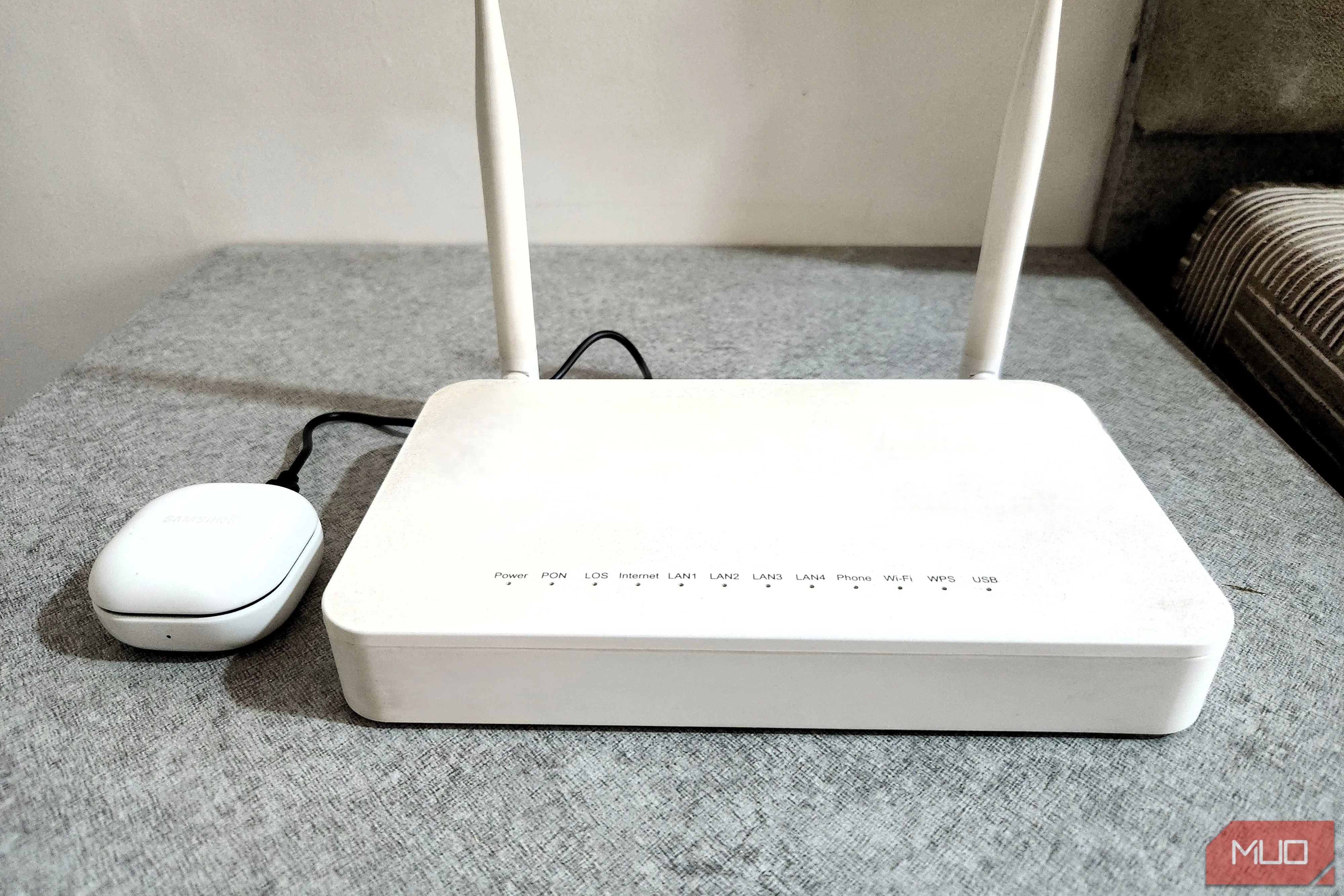 Tai nghe Bluetooth đang sạc qua cổng USB của router, minh họa khả năng sạc các thiết bị nhỏ tiện lợi