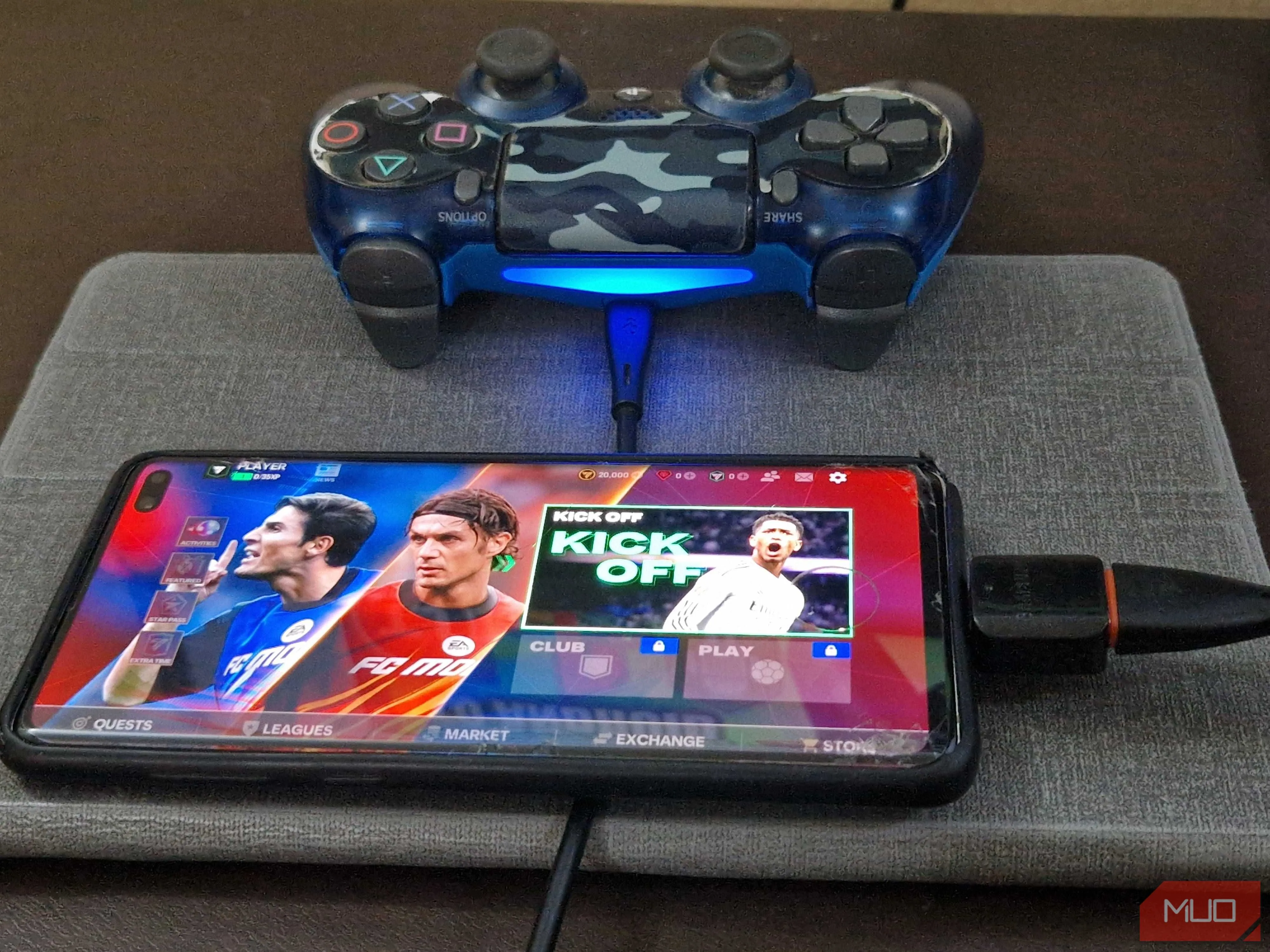 Tay cầm PS4 được kết nối với điện thoại thông minh qua bộ chuyển đổi OTG và cáp USB để chơi game di động.