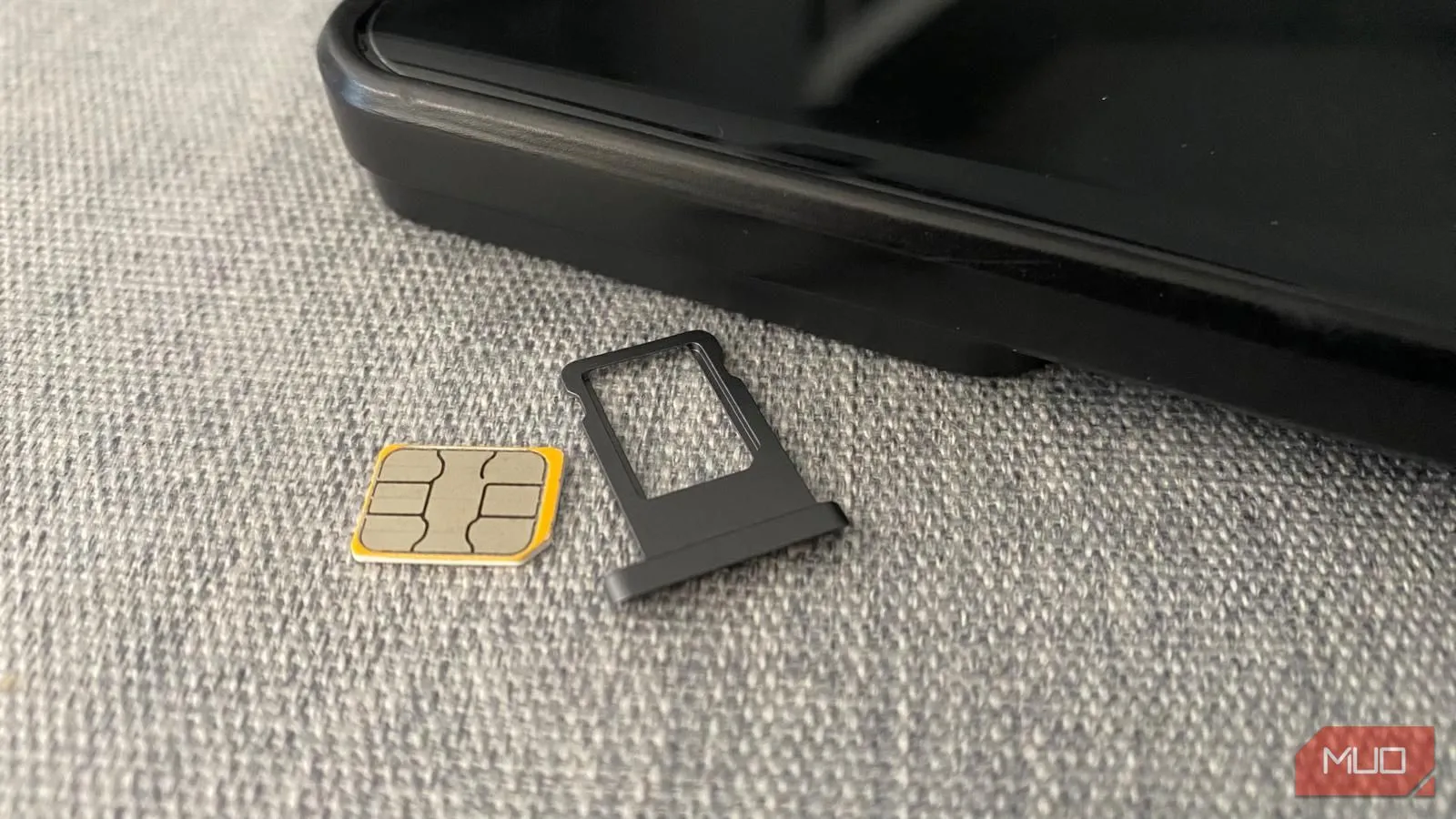 Thẻ SIM vật lý và khay đựng đặt cạnh điện thoại di động trên bàn