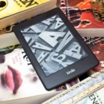 Thiết bị đọc sách Kindle đặt trên chồng sách vật lý, minh họa cho thư viện eBook của Amazon